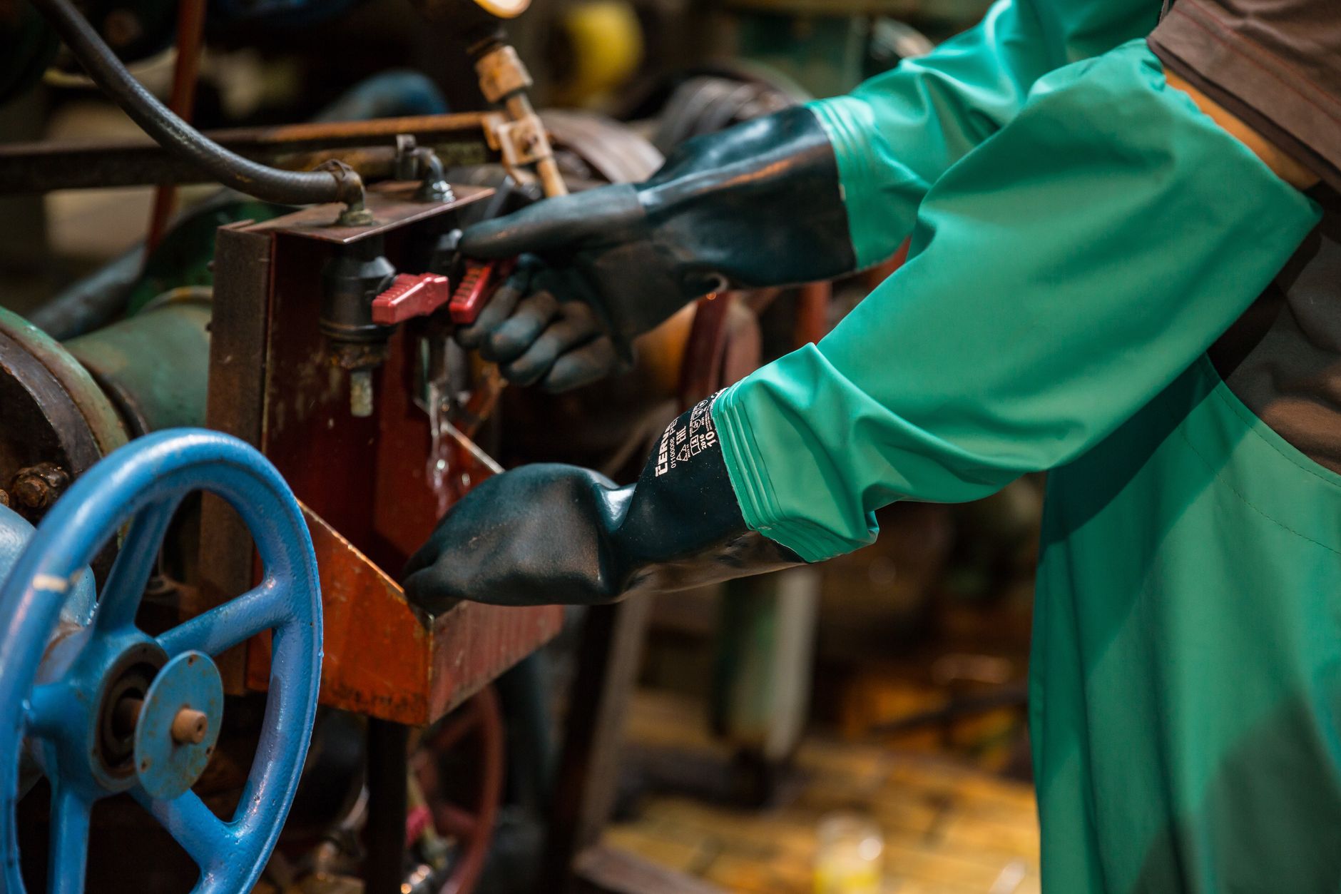 Cut-resistant gloves at an industrial bench, a reminder that sharp parts still need manual handling at staging.