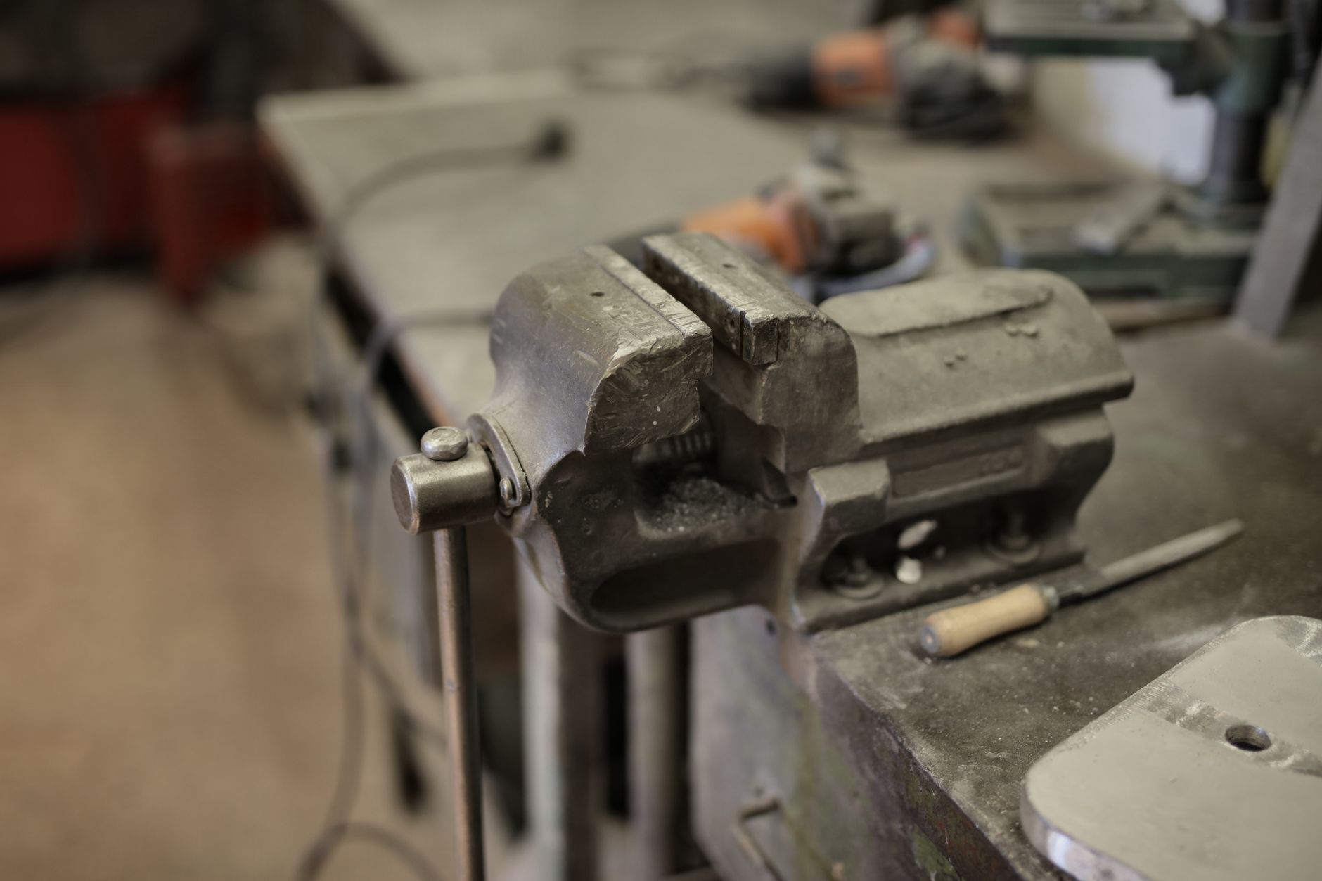 Bench vise and fixtures on a toolroom table, illustrating the clearance a loader arm needs at the machine door.