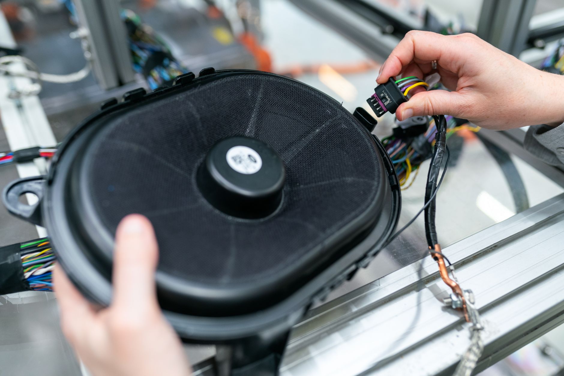 A technician assembles a branched wire harness at an electronics workbench, representing the skilled manual work retained alongside cobot assistance.