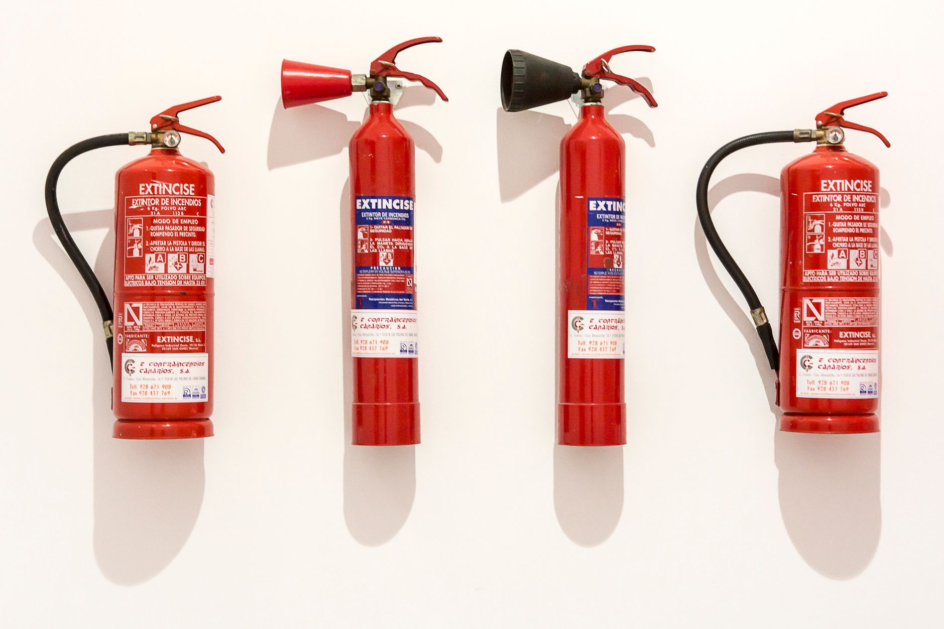 Red CO2 fire extinguisher mounted on a wall beside industrial equipment.