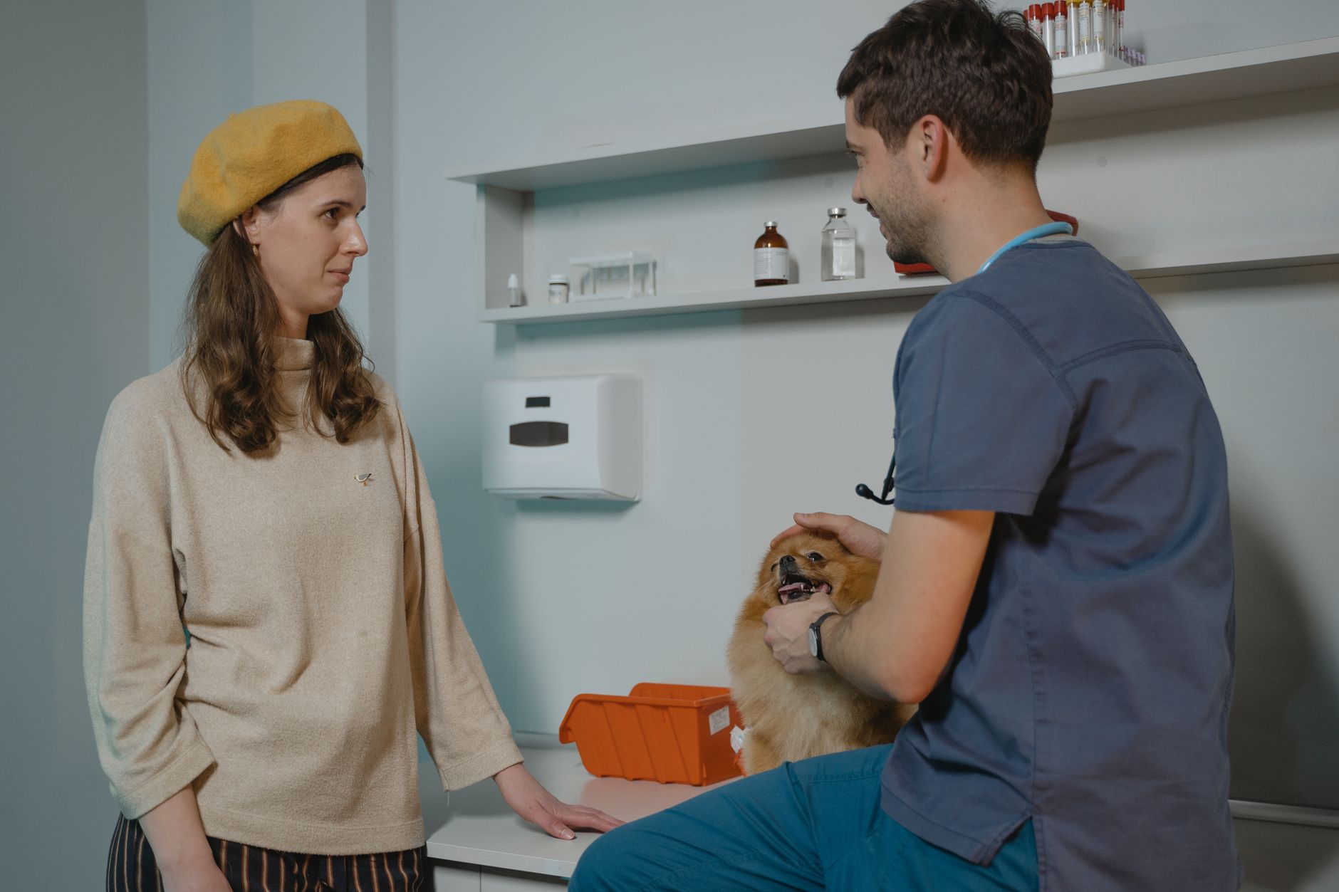 A busy clinic reception area where robots must yield to leashed pets and staff.