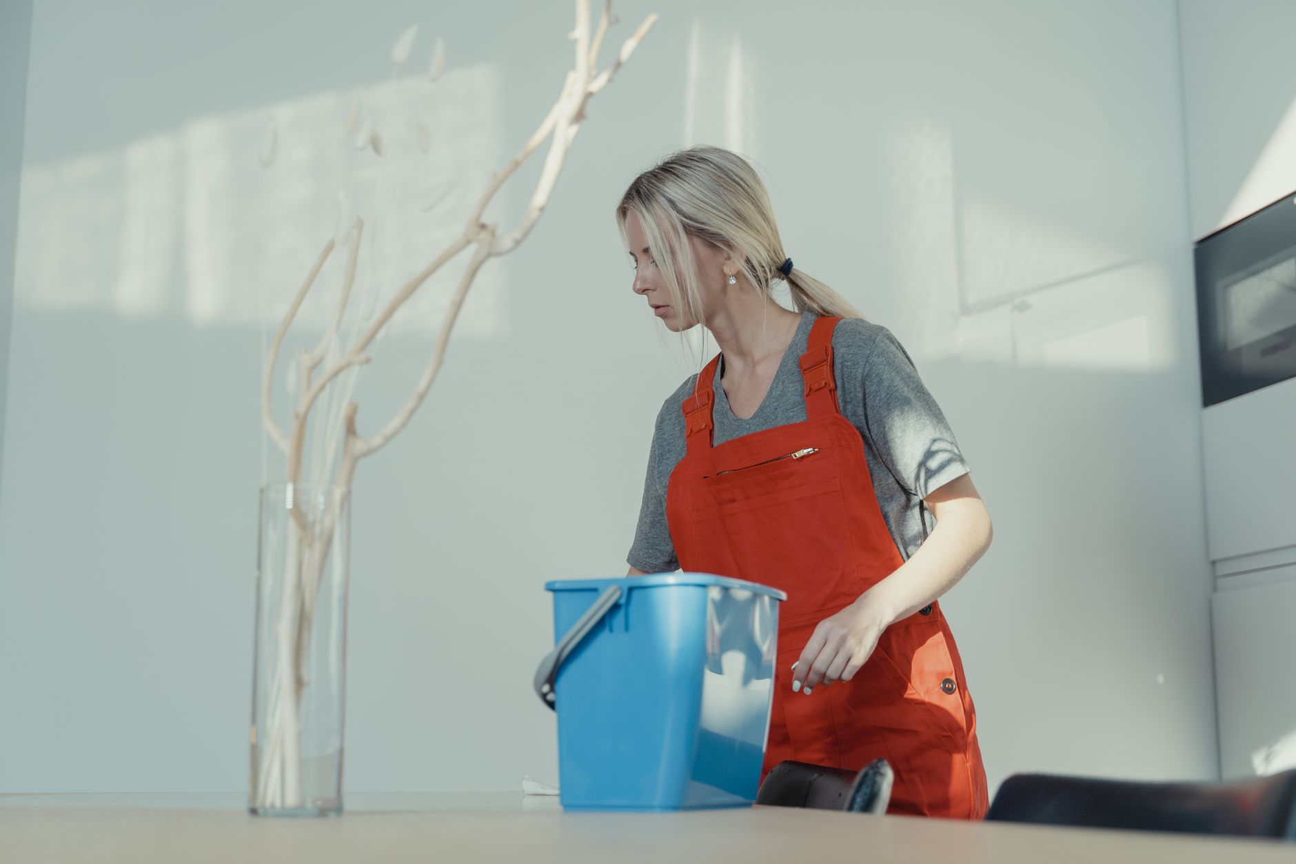 A custodian rinses wet-cleaning equipment as part of the maintenance needed to prevent residue buildup.