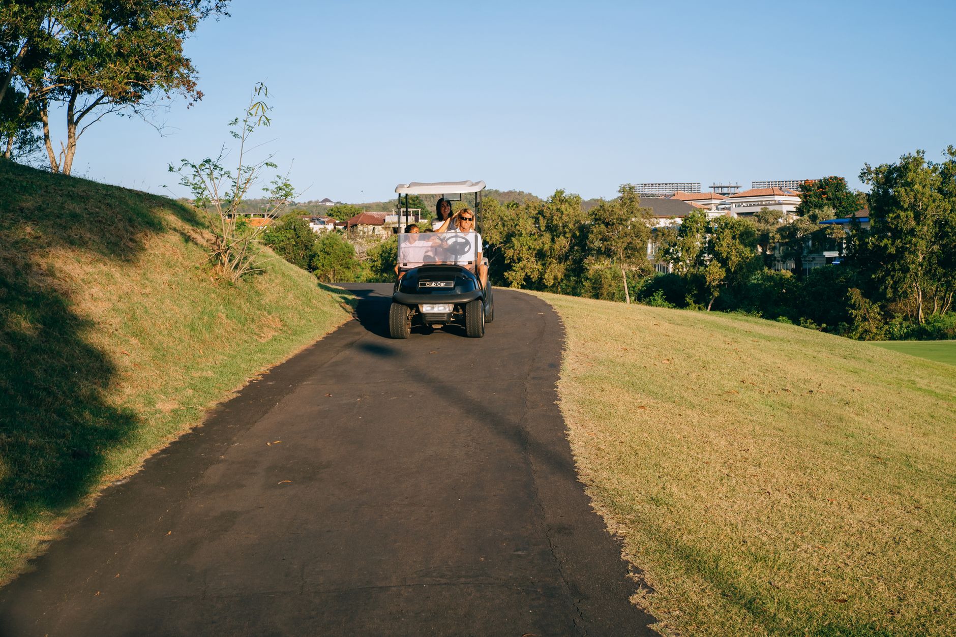 A paved cart path curving along the edge of a golf fairway at dawn.