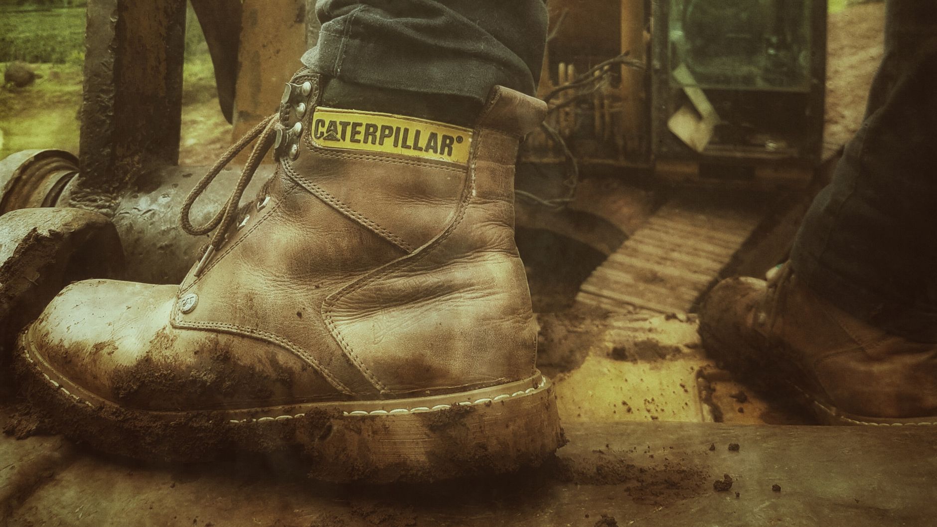 Muddy work boots on a floor mat at a building entrance