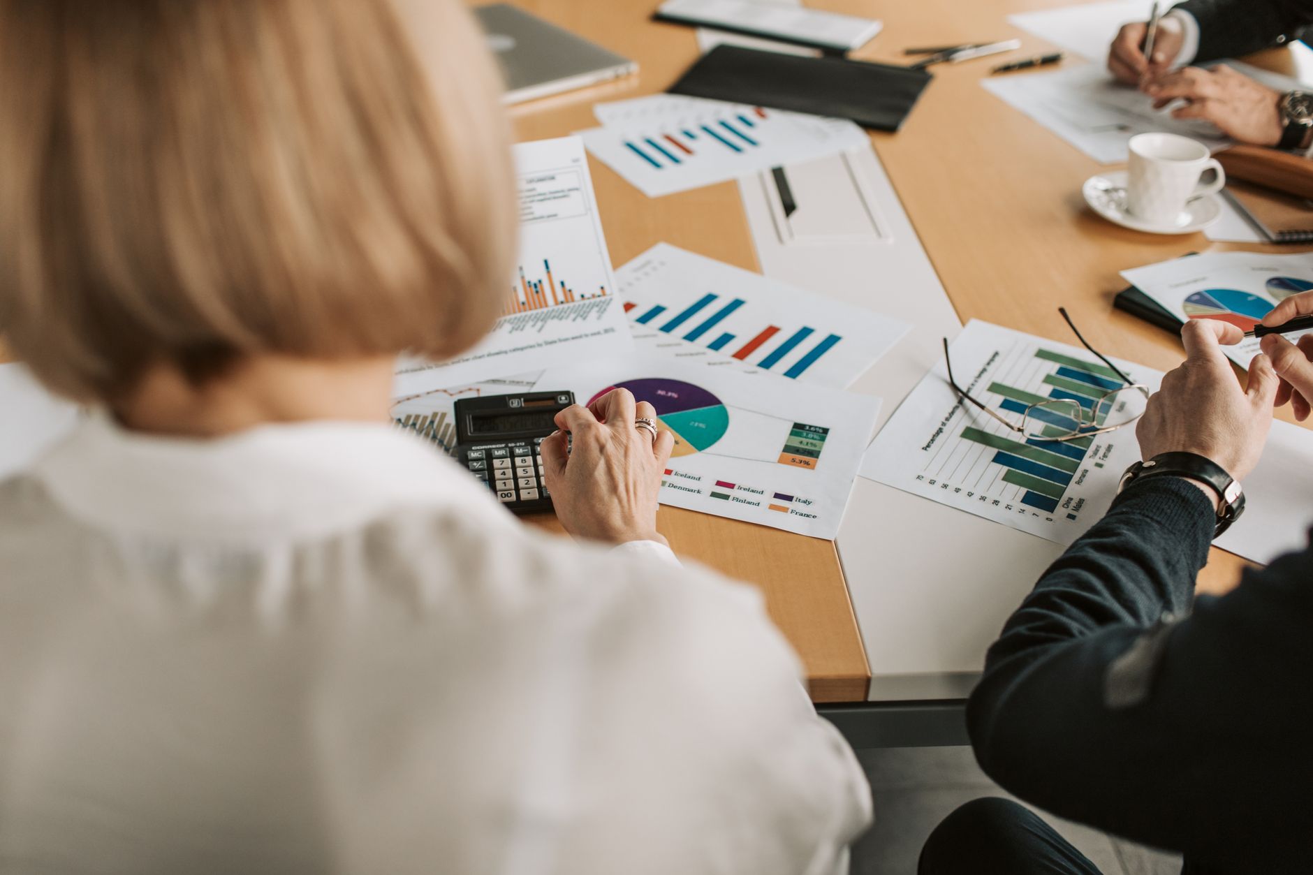 A team of professionals in a meeting room review charts and graphs, representing the financial decision-making process for acquiring a robot fleet.