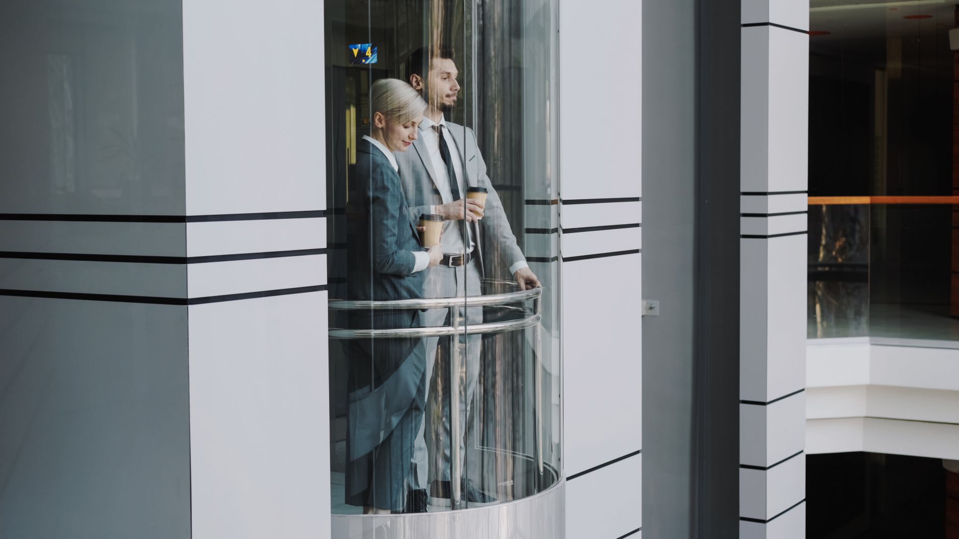 A row of sleek, stainless steel elevator doors in the quiet, empty hallway of a multi-story office building.