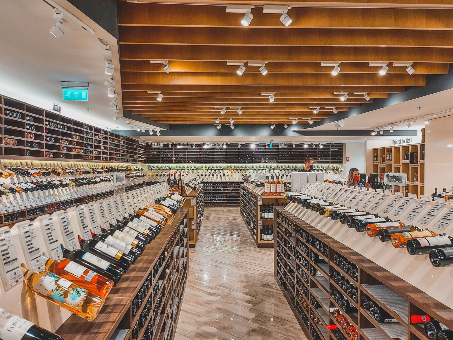 A wide, gleaming aisle in a modern supermarket shows off a highly polished and reflective concrete floor, ready for customers.