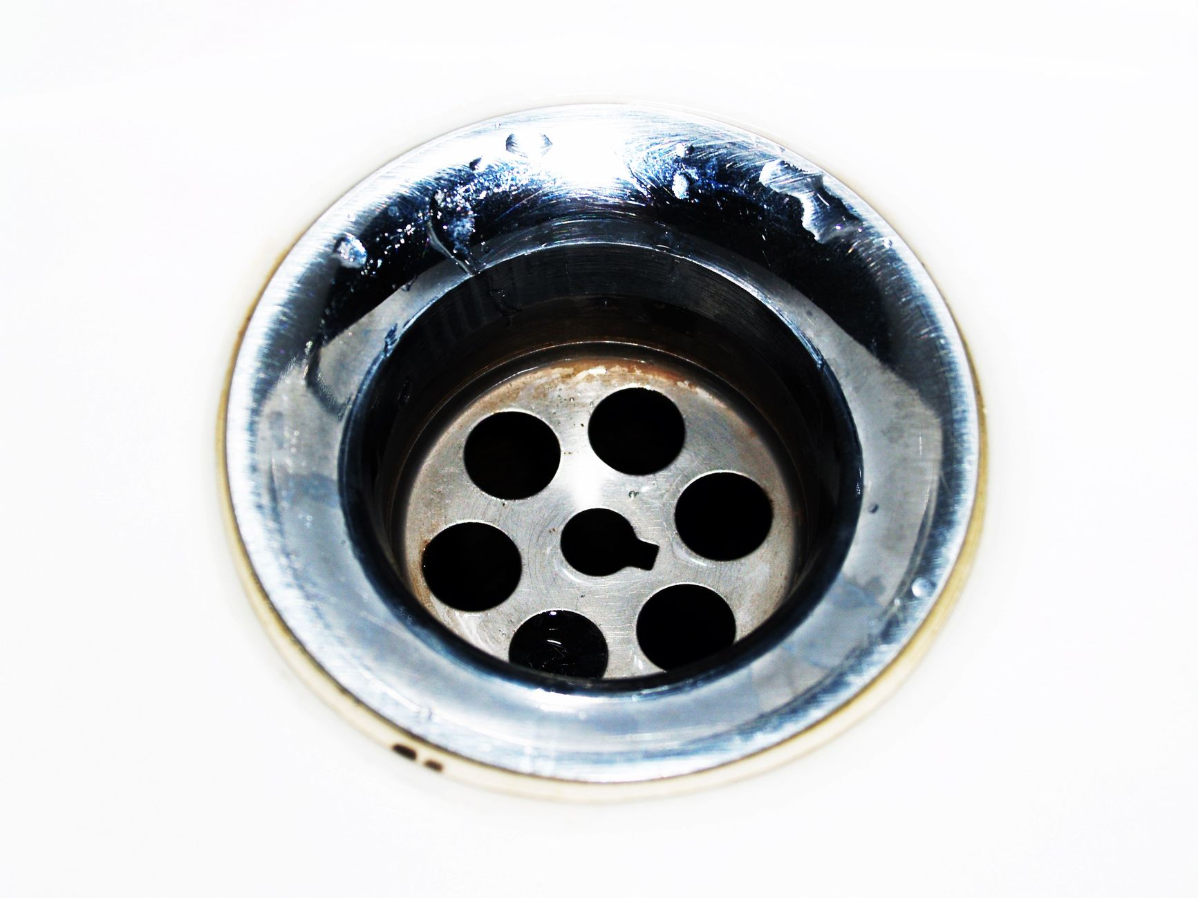A stainless floor drain set into sloped concrete, the kind scrubber routes must reach after sanitation.