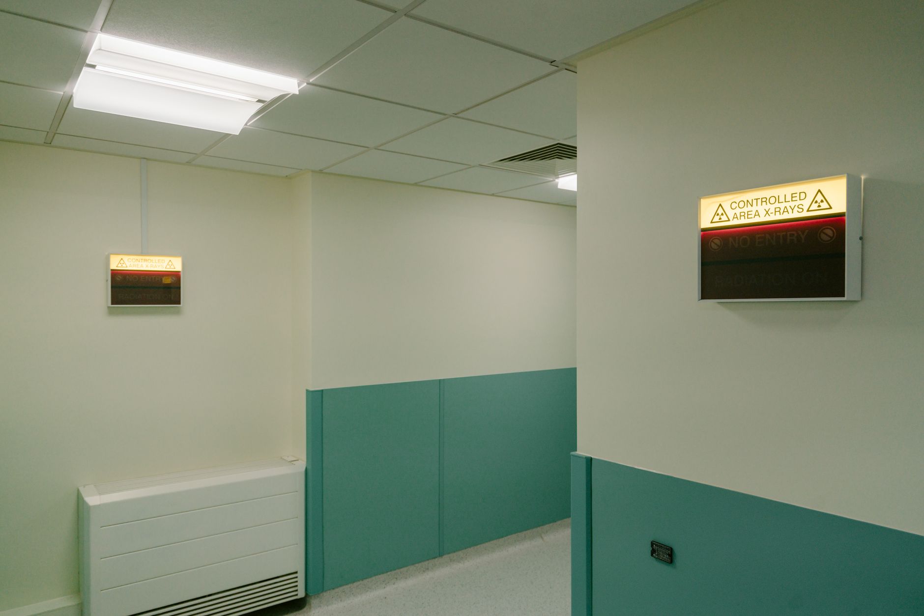The clean, bright intersection of two long hospital corridors, representing a complex space where automated traffic deconfliction prevents gridlock.