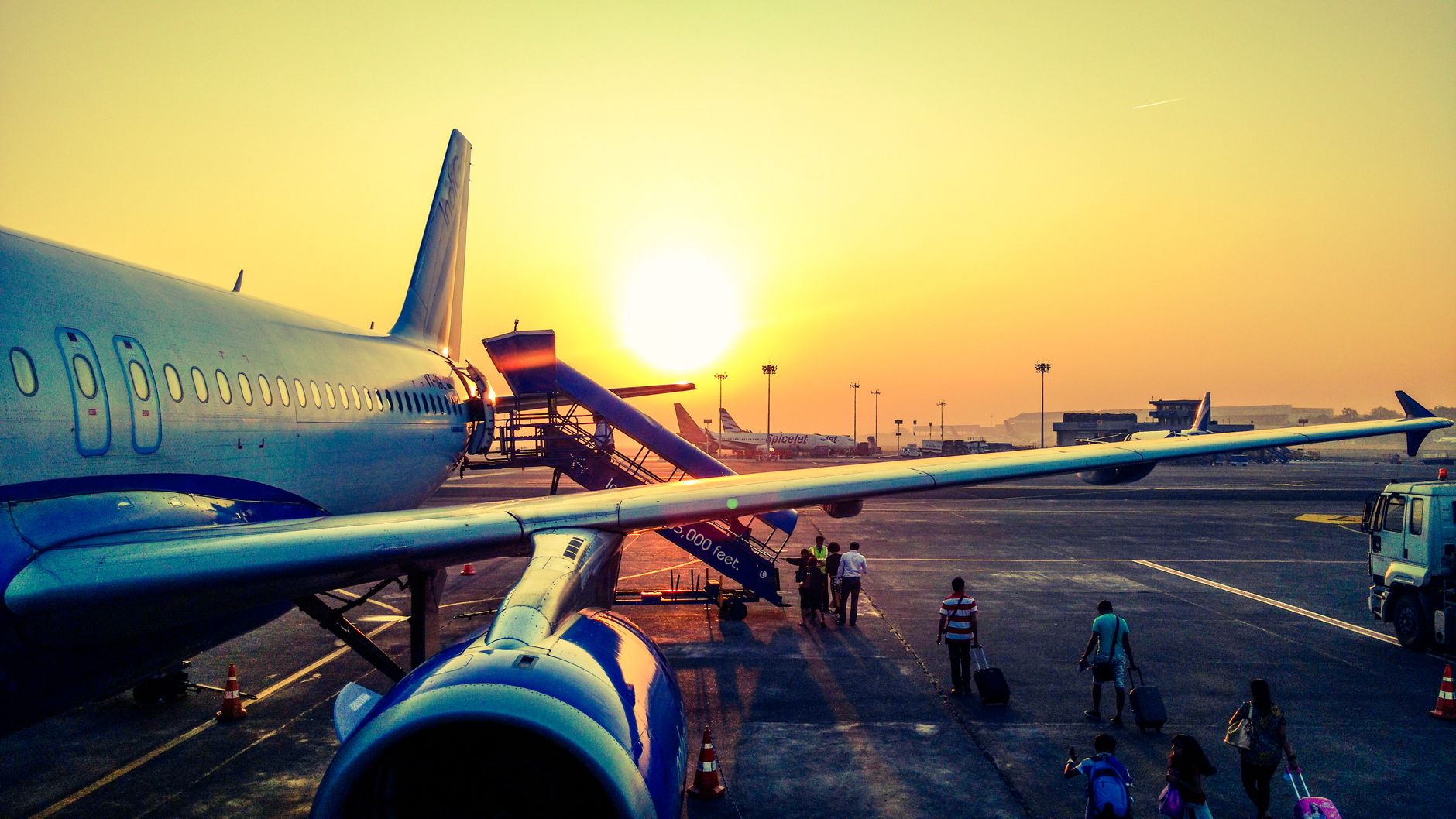 Sunlight streams through the large windows of a modern airport terminal, casting long shadows across the empty gates and waiting areas.