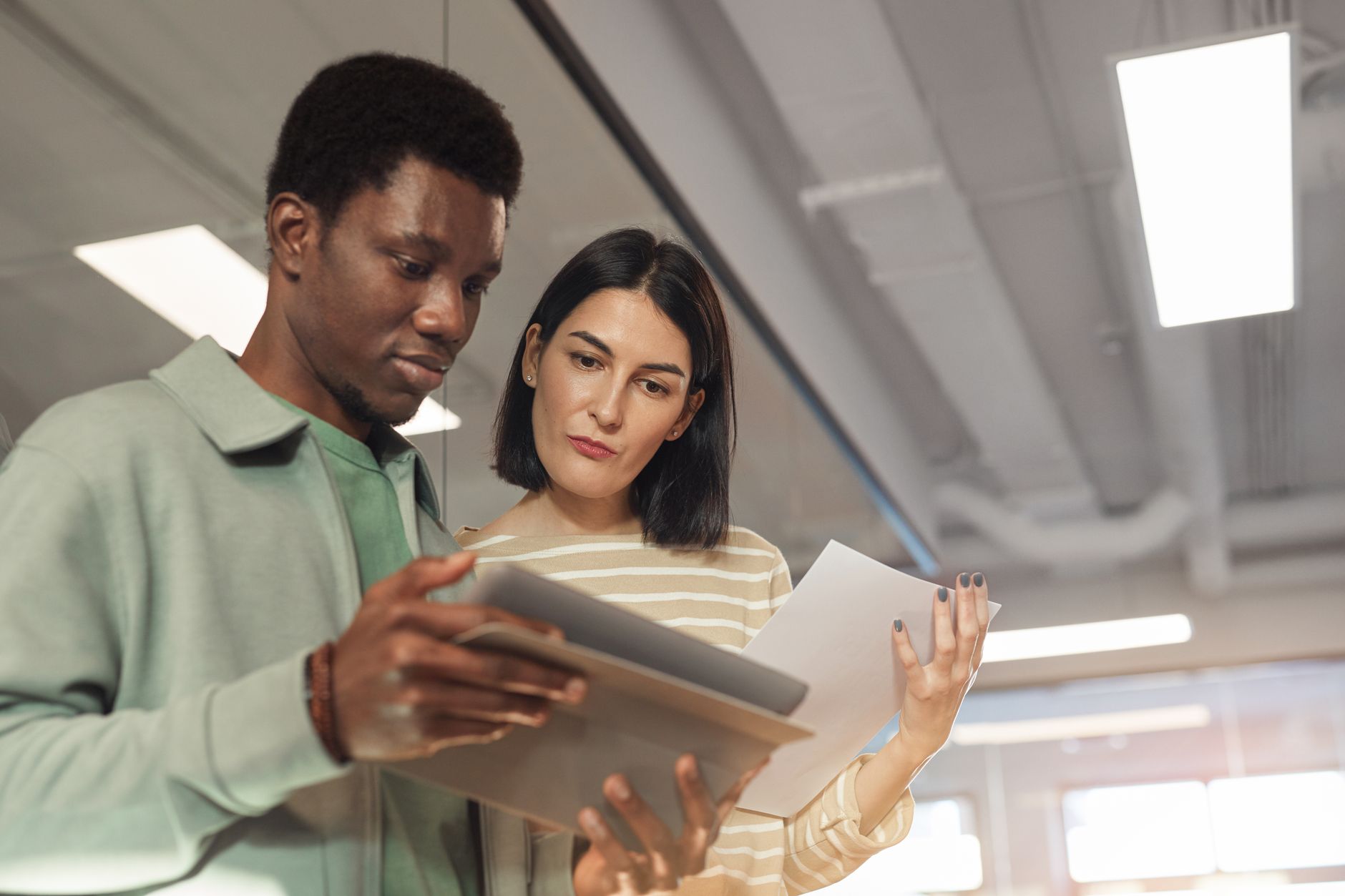 Two employees in uniform collaborate, with one pointing to a tablet, representing peer-to-peer training and support for new robotic systems.