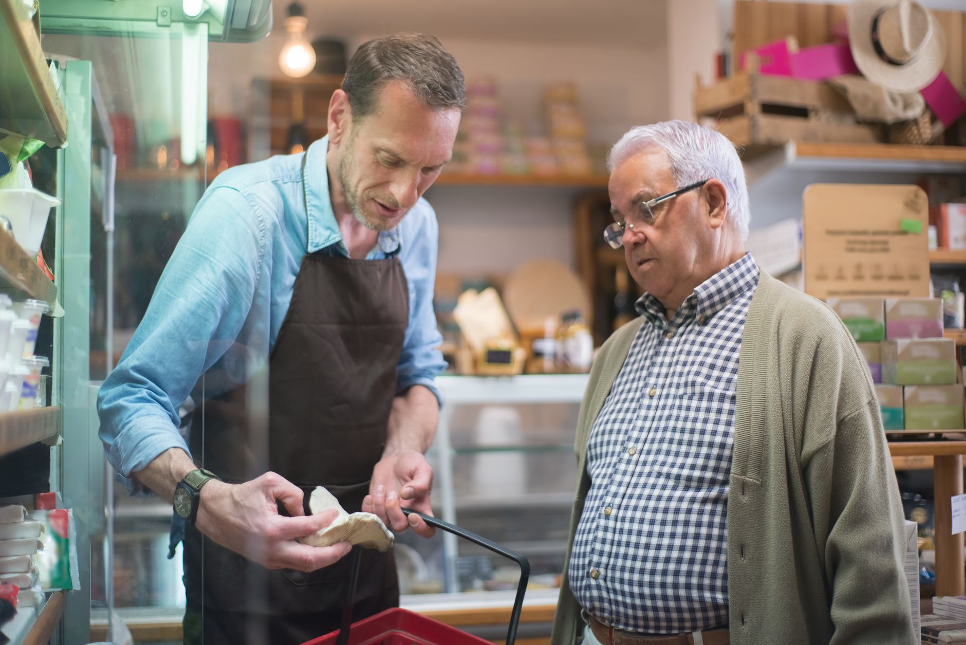 A grocery store employee smiles while assisting a customer, with the focus on human interaction in a clean environment.