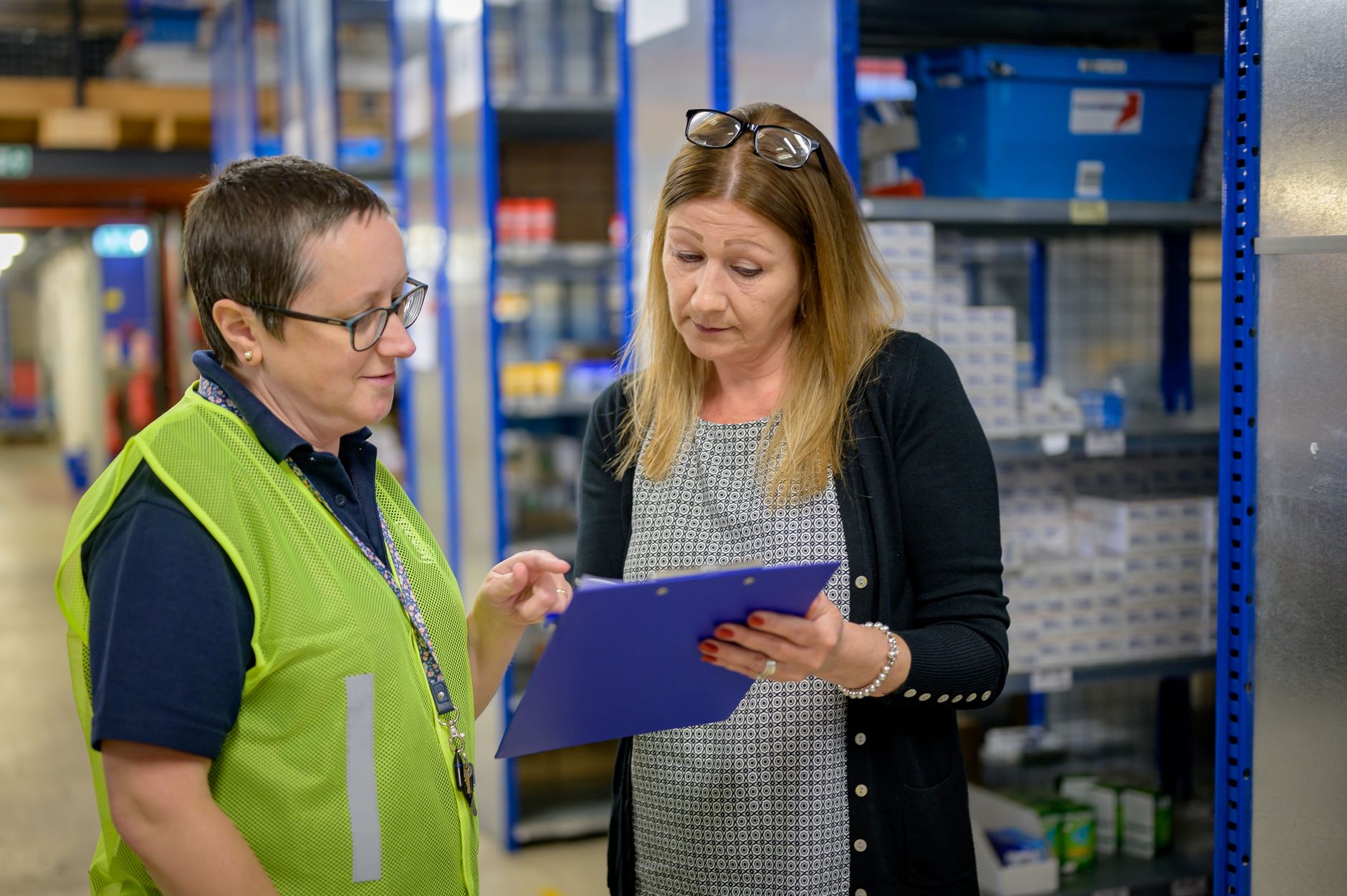 A warehouse supervisor reviewing floor activity with a clipboard, underscoring the service, training, and response discipline needed after go-live.