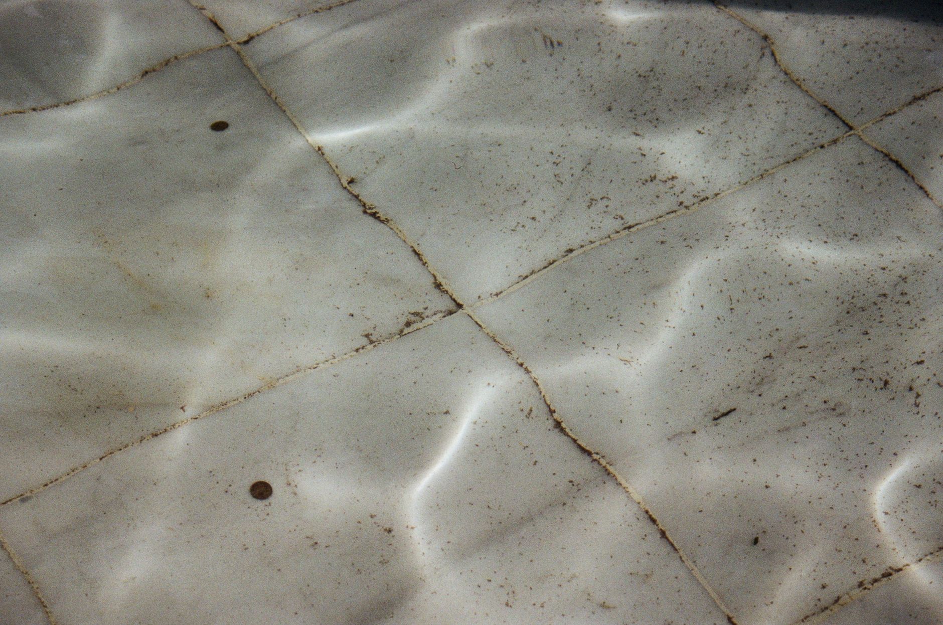 A close-up of a dirty commercial floor showing tracked-in grime and sticky residue, illustrating a typical laundromat cleaning challenge.