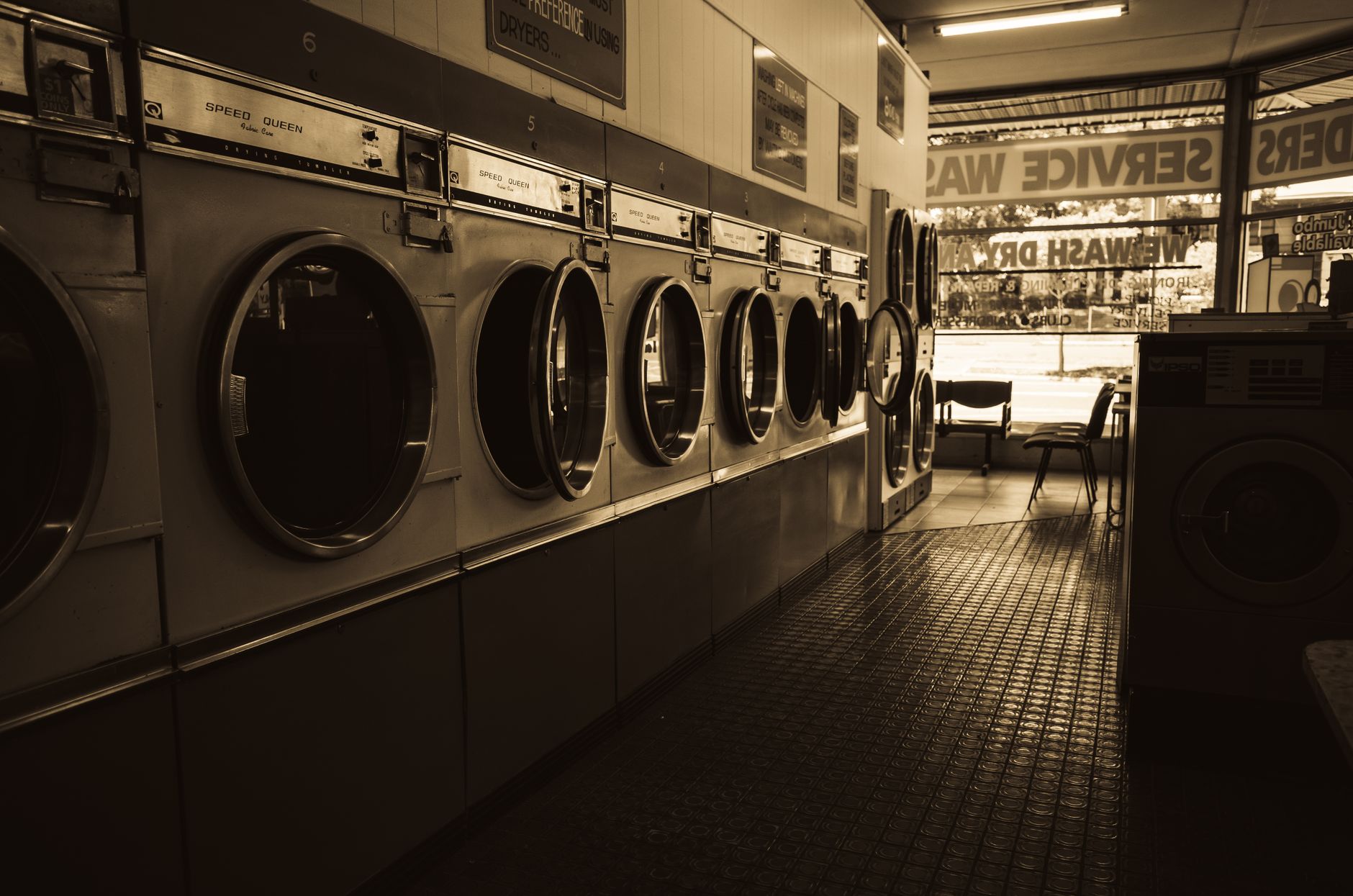 A clear, unobstructed aisle between washing machines in a laundromat, prepared for an autonomous floor scrubber to operate.