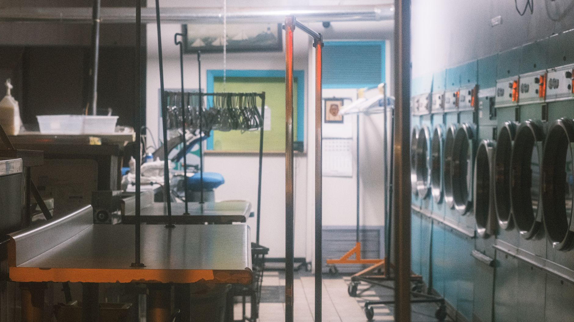 A bright, clean, and empty modern laundromat with rows of washers and dryers, its spotless floor reflecting the overhead lights.
