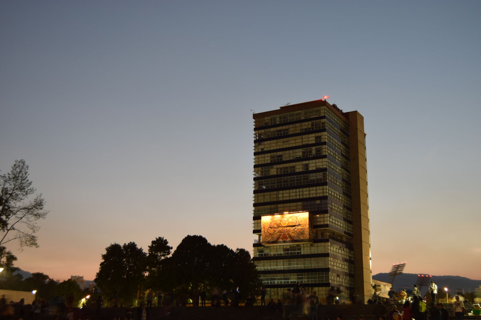 A sweeping view of a well-lit modern university campus at dusk, conveying a sense of scale and safety.
