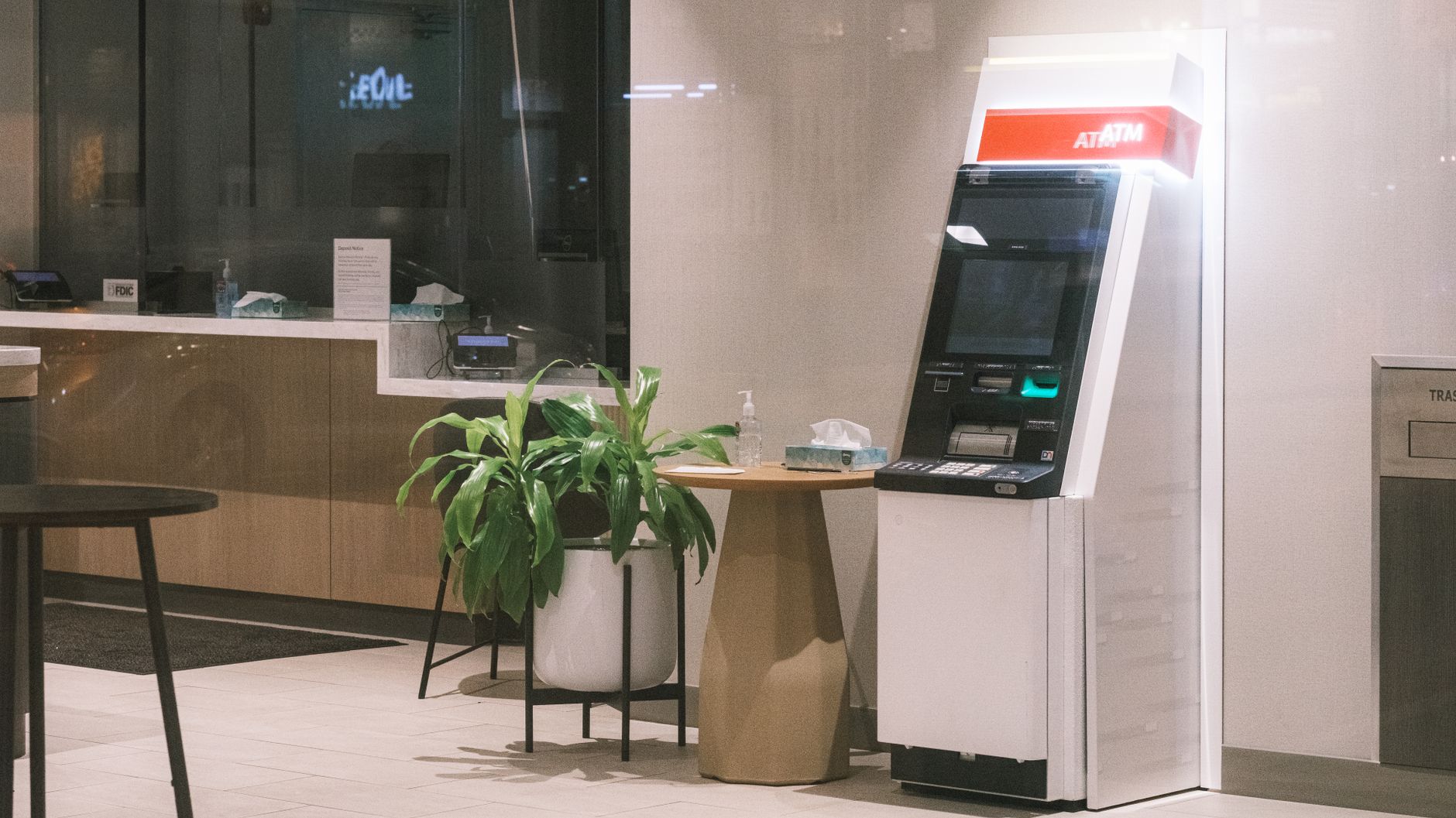 A quiet branch banking area with teller counters and close customer conversation zones where equipment noise would stand out.