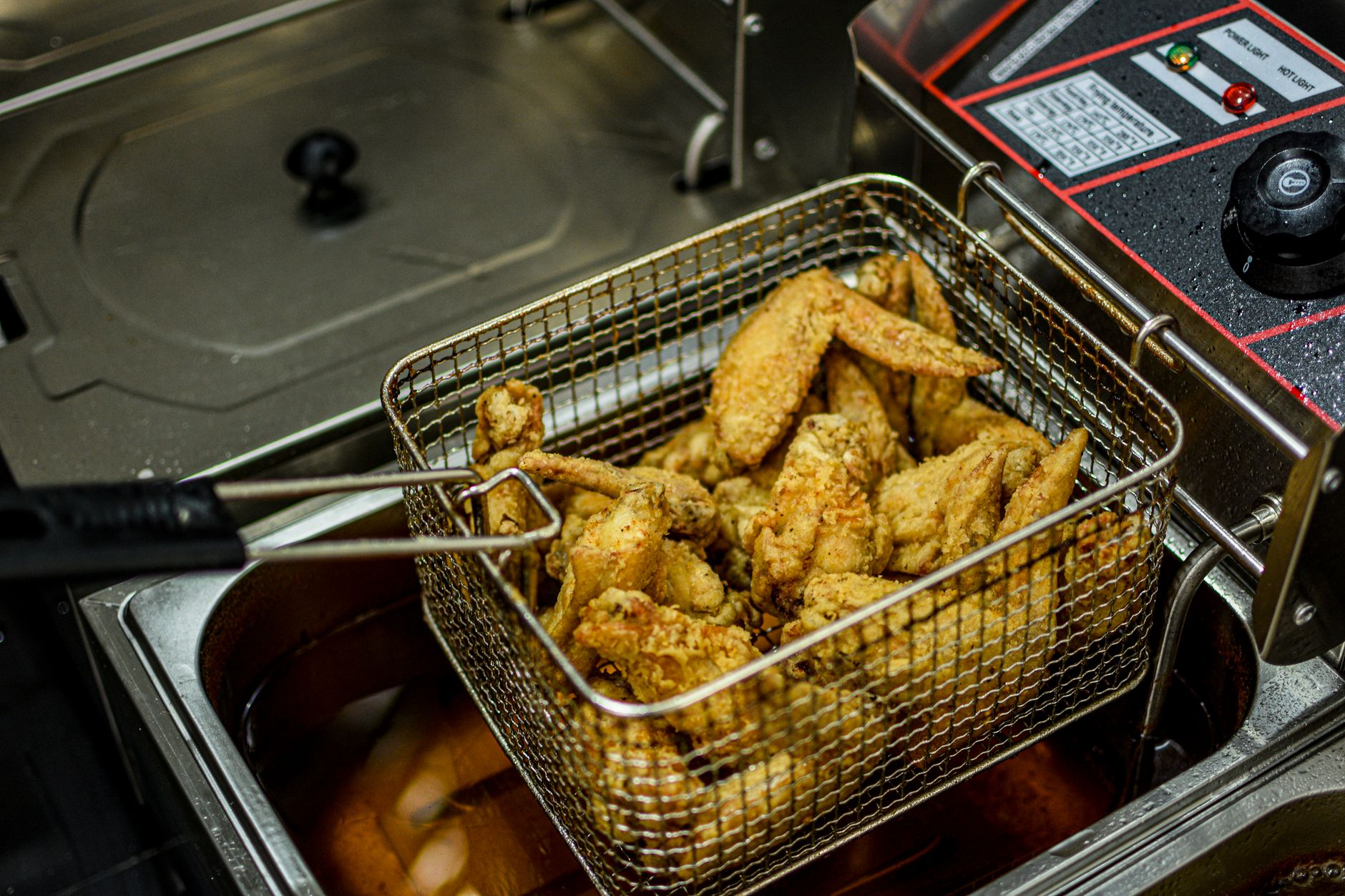A wire fryer basket filled with perfectly cooked, golden-brown french fries in a commercial kitchen, an example of automated precision.
