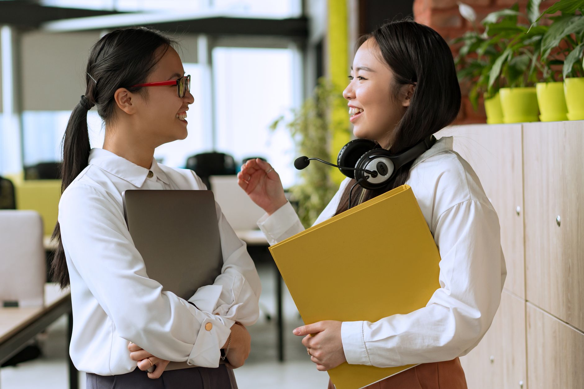 Two smiling, valued employees having a positive conversation in a bright, modern office space, representing the human benefits of automation.