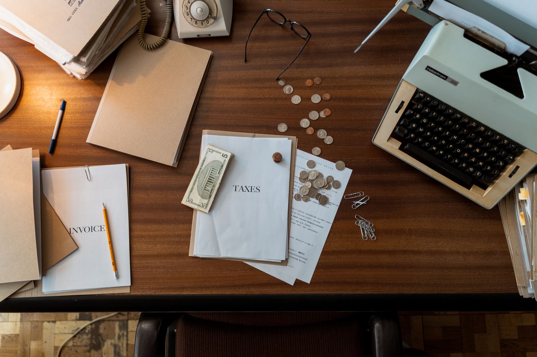 An accounts payable reviewer compares printed service invoices against a laptop ledger during a monthly vendor audit.