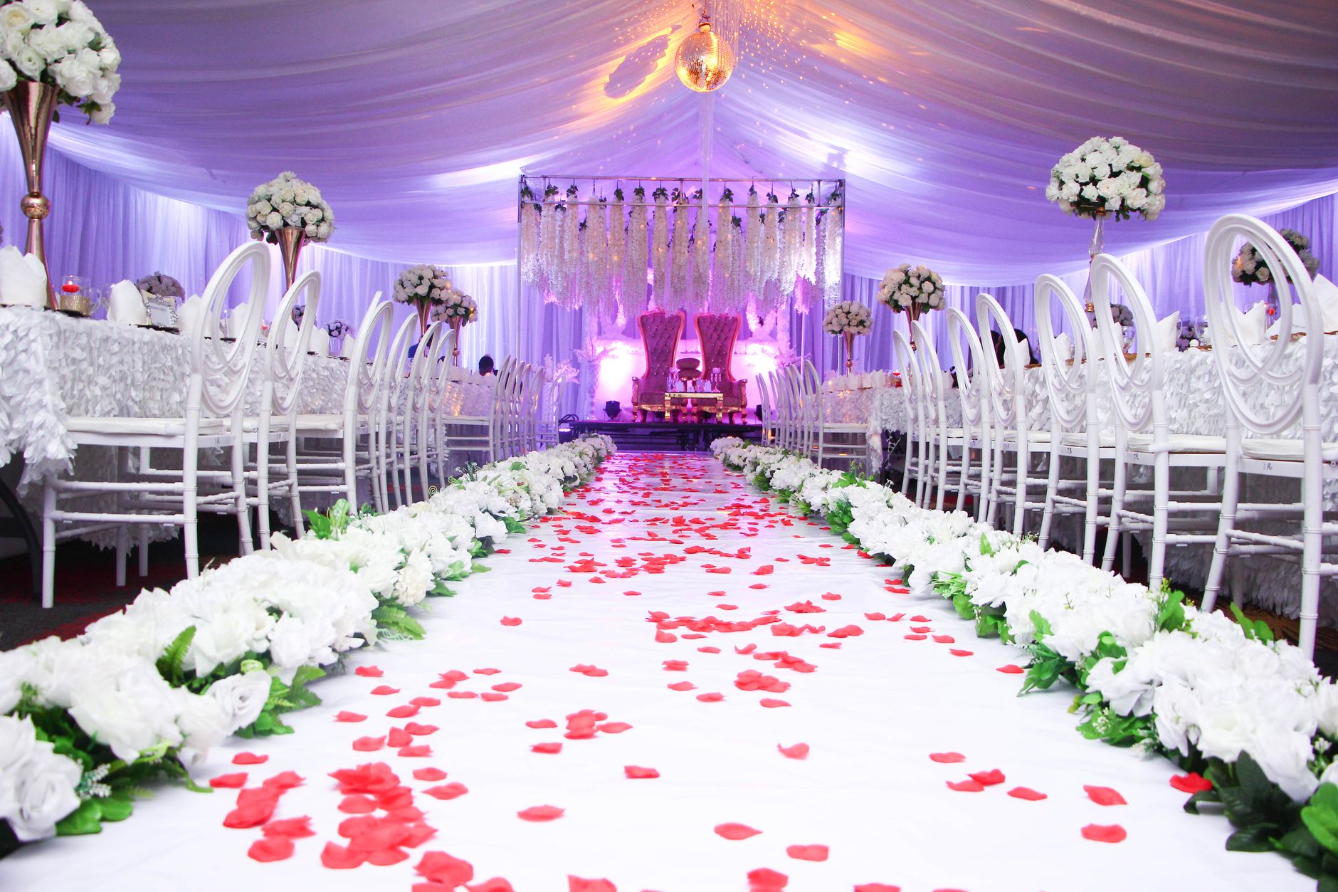 Closely arranged tables and chairs leave a defined central aisle through a busy hall layout.
