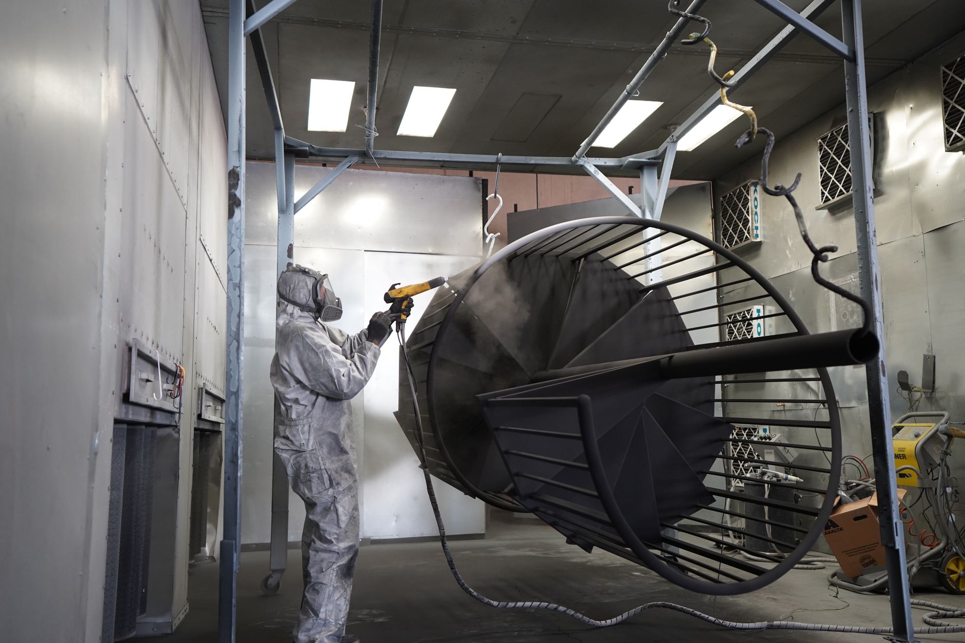 An automotive paint booth area with masking and refinishing equipment, representing the hazardous, contamination-prone zone the article says should stay manual at first.