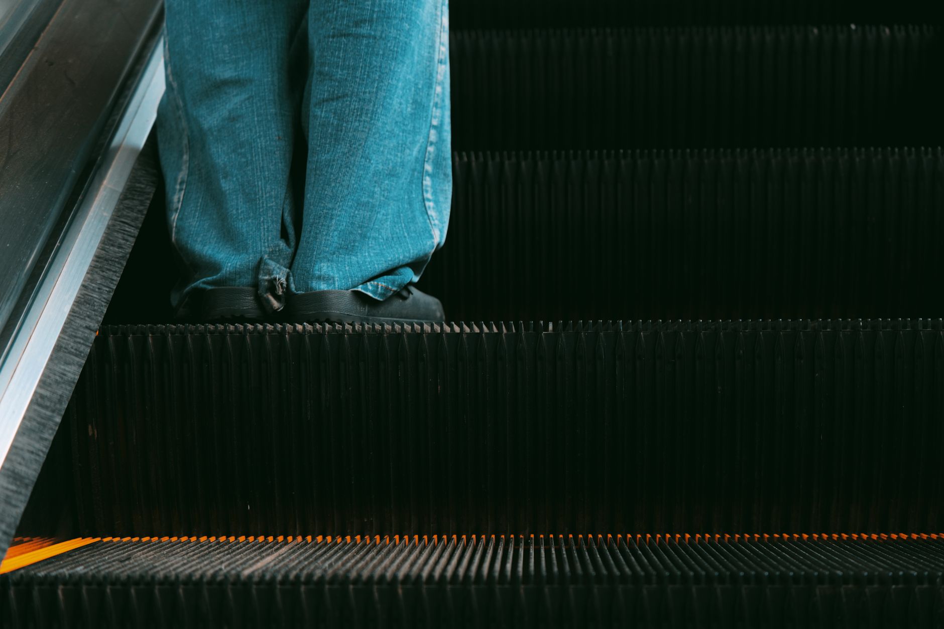 A close view of the marked step edges and comb-plate area at an escalator landing.