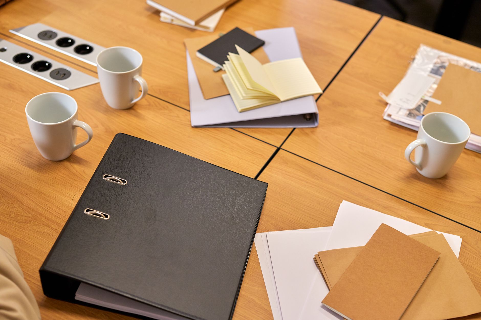 Procurement documents spread across a meeting table reinforce why buyers need a second worksheet beyond the headline robot quote.