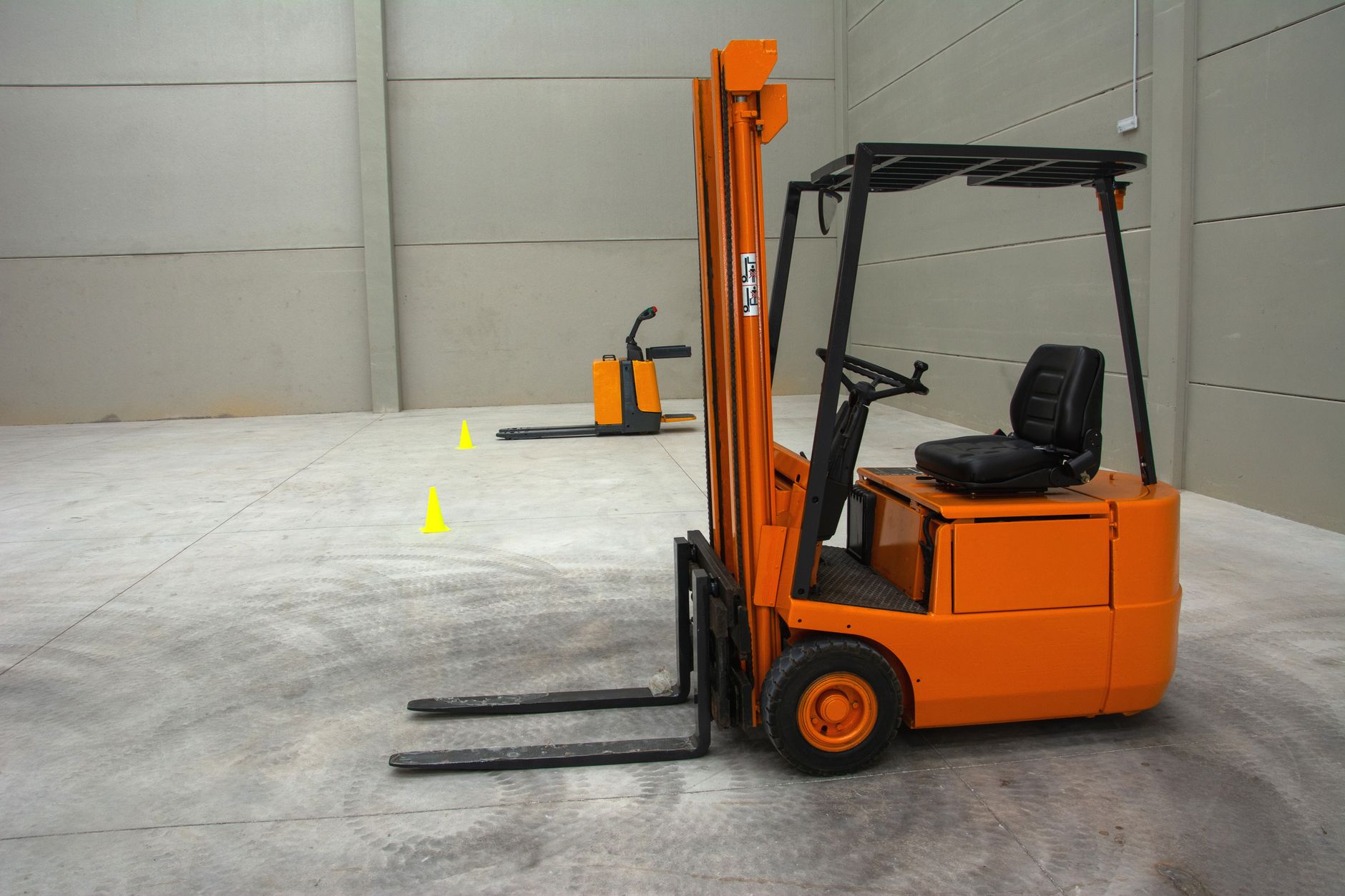 A warehouse team conducts supervised forklift safety training near marked loading lanes.