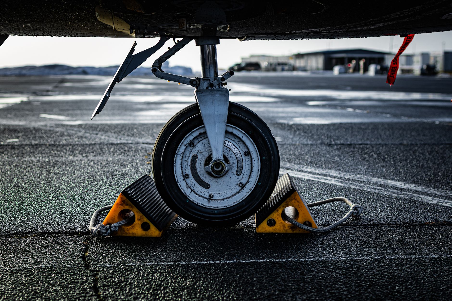 A wheel chock secured against a parked trailer tire beside a loading dock.
