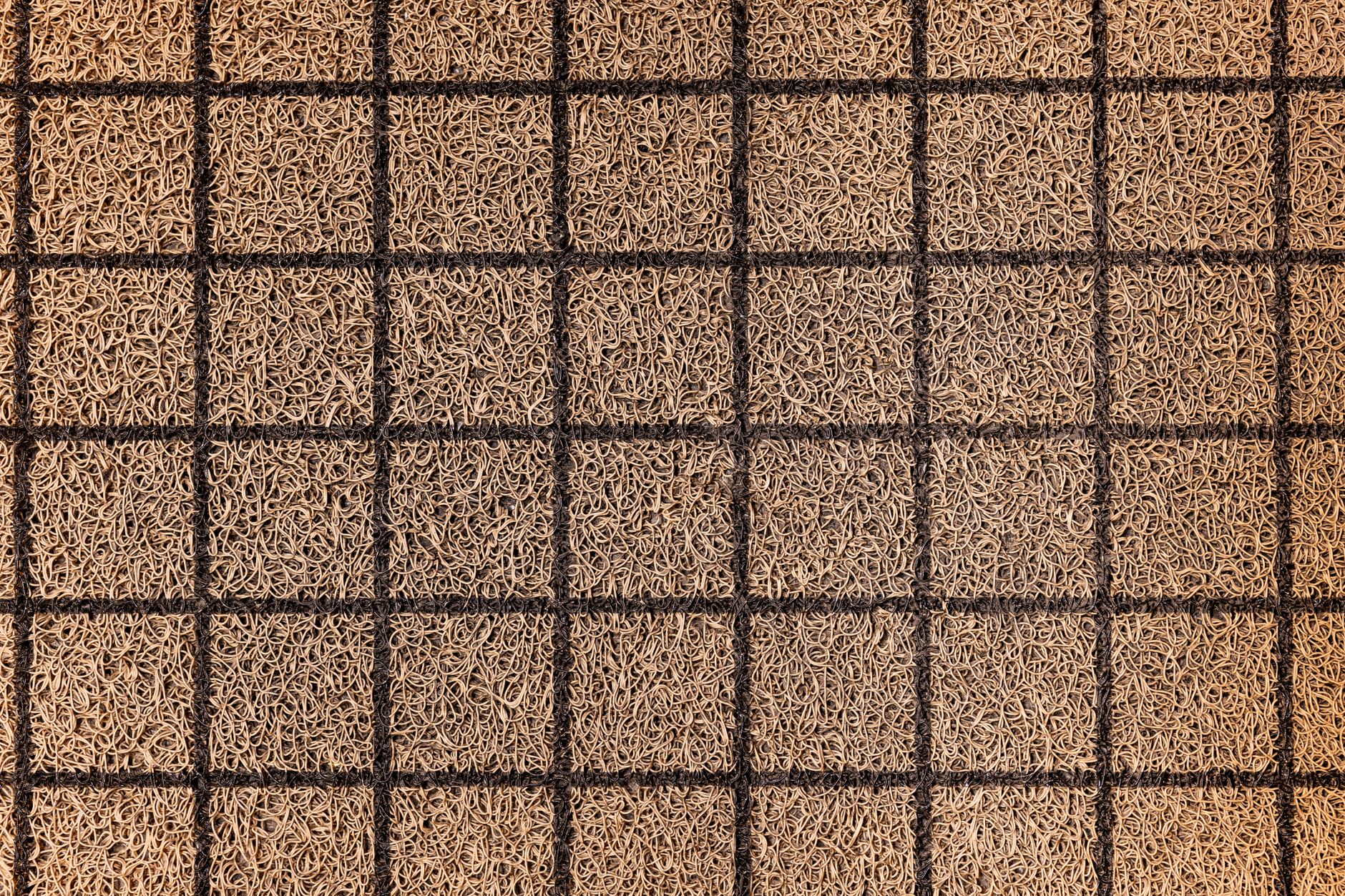 A close view of a commercial entry mat meeting hard flooring, showing the kind of threshold and transition detail buyers need to inspect in a funeral home route.