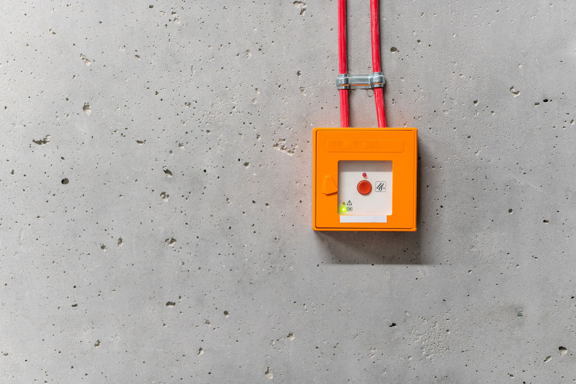 A red emergency stop button mounted where warehouse staff can reach it during a drill.
