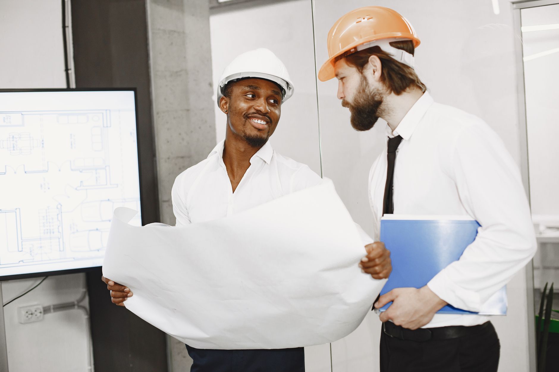 A procurement manager and an engineer review technical plans for a robotics integration project at a conference table.