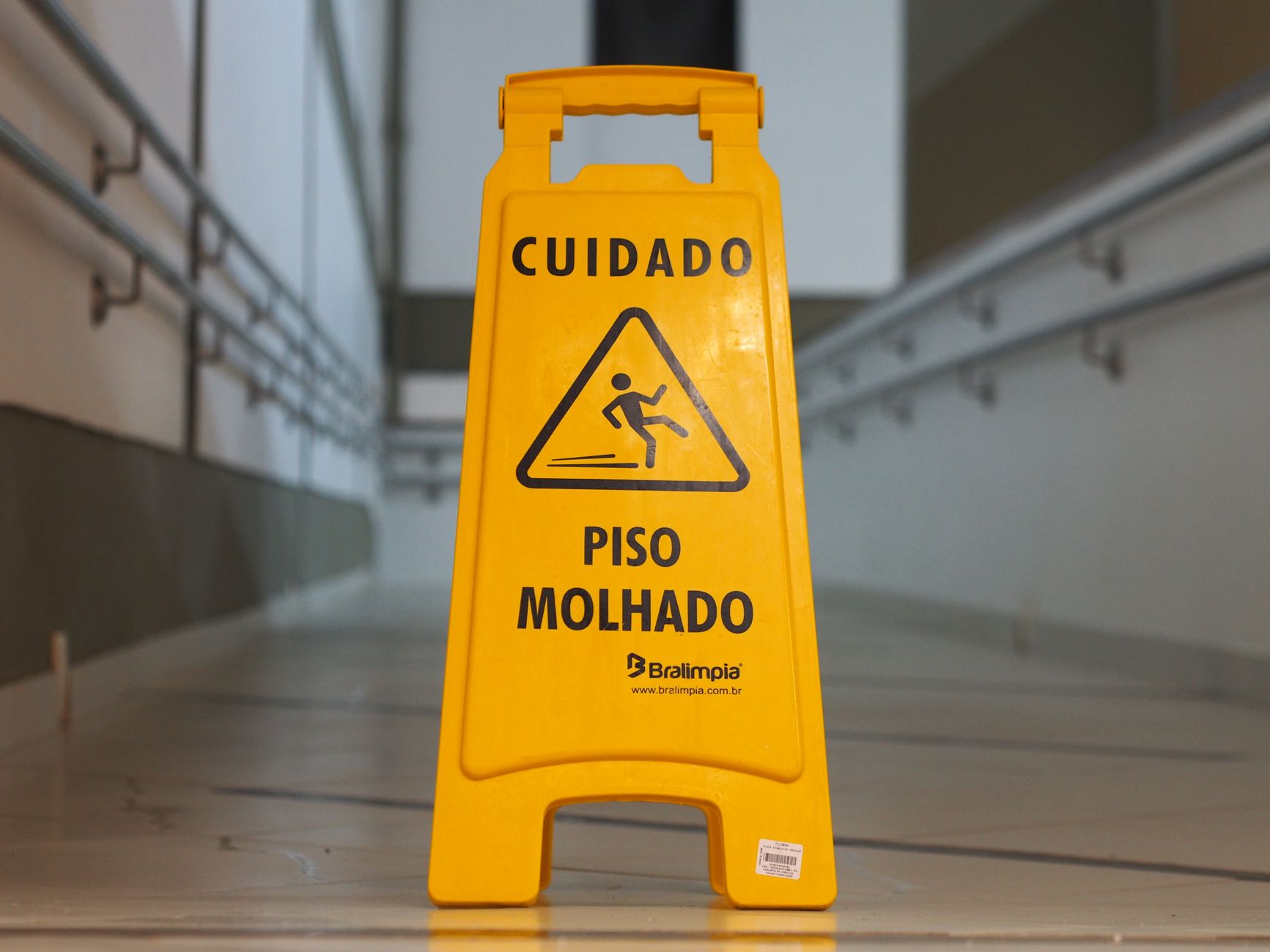 Hard-surface corridor in a sports facility being kept dry and clear to reduce slip risk near courts and restrooms.