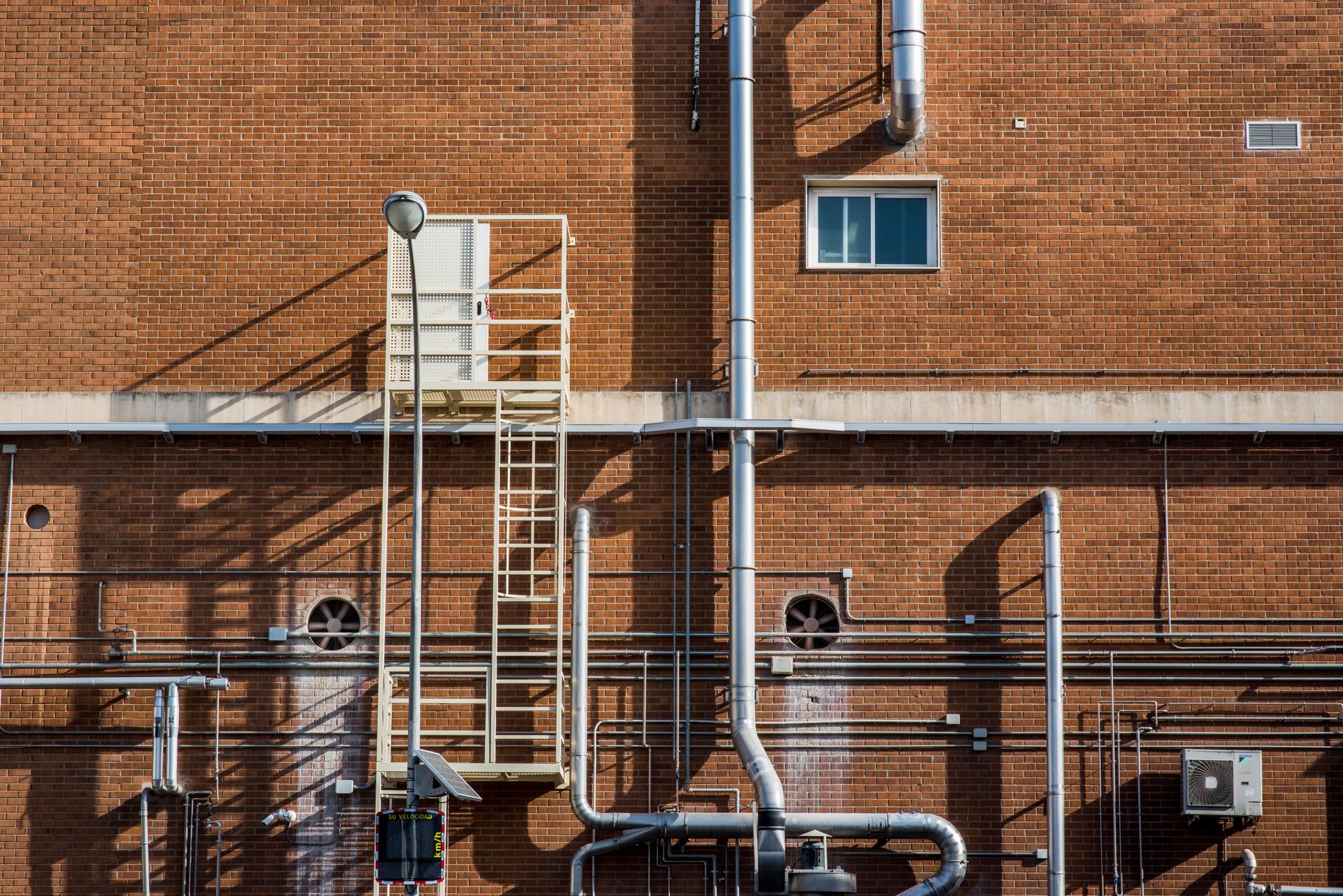 Tight mechanical access area with ladder, piping, and hard surfaces, showing the kind of confined infrastructure where human entry still requires formal safety controls.
