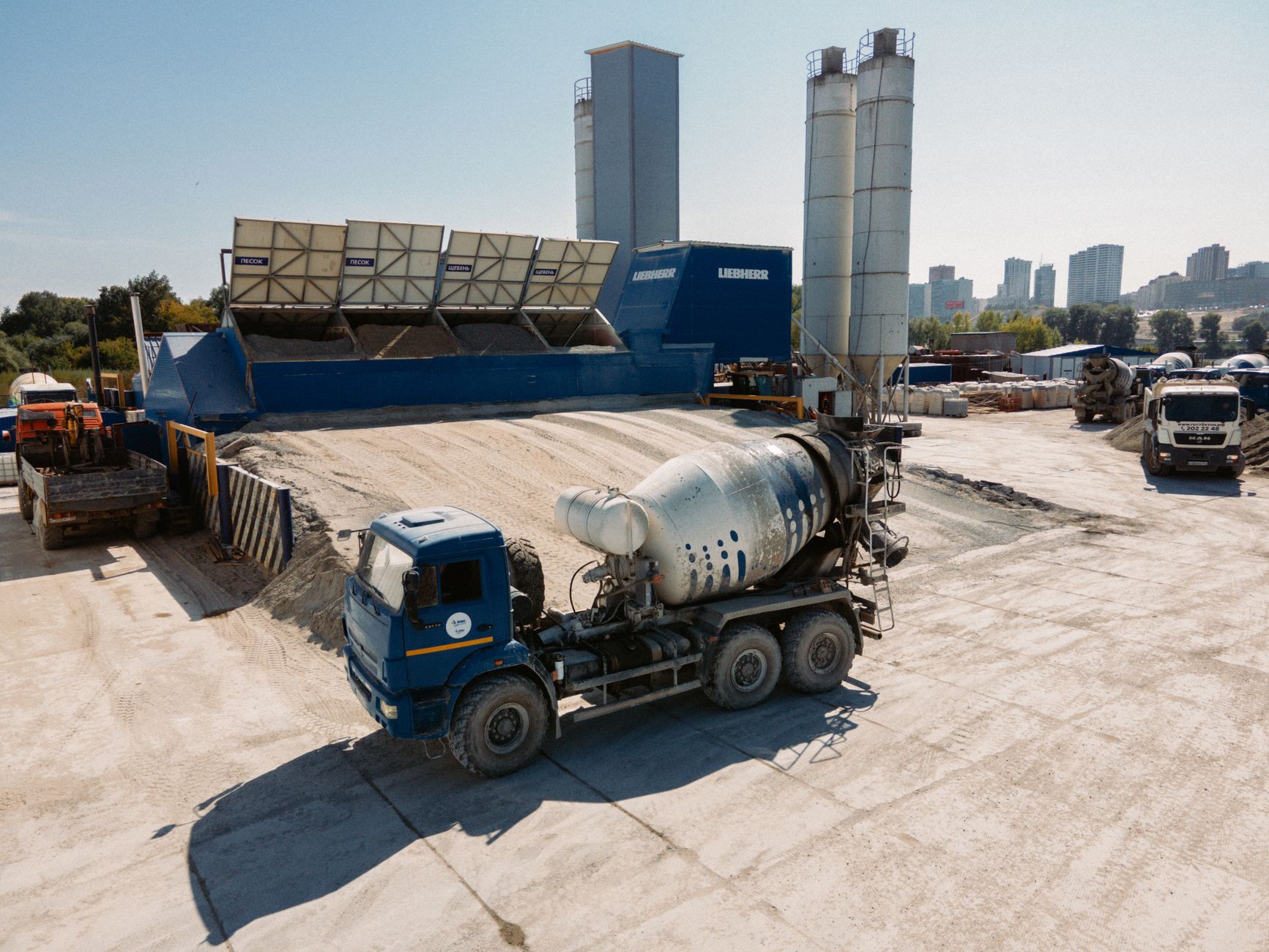 Outdoor concrete batch plant with conveyors and aggregate bins where mobile inspection routes run.