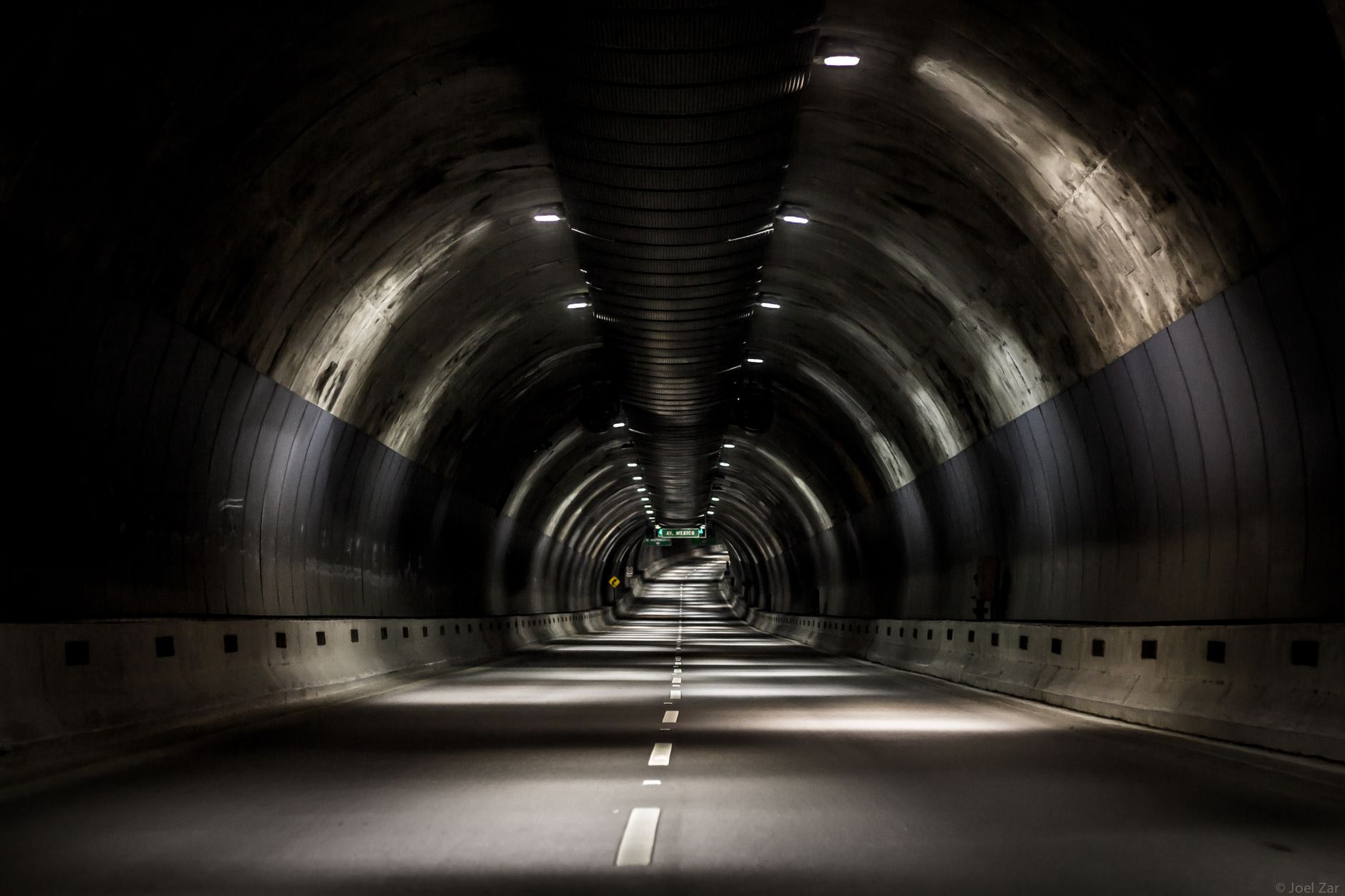 Bright industrial lighting along a dark service corridor, similar to the panels needed inside a transfer chute.