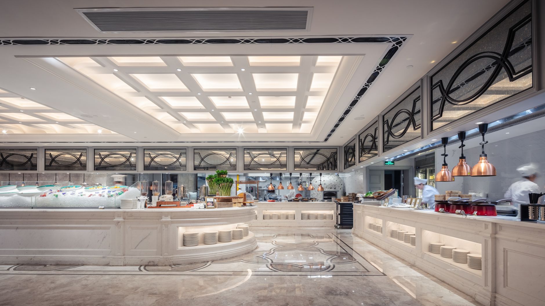 A long commercial kitchen interior with overhead hood runs and tight ceiling space, showing why exhaust-path geometry matters before an inspection.