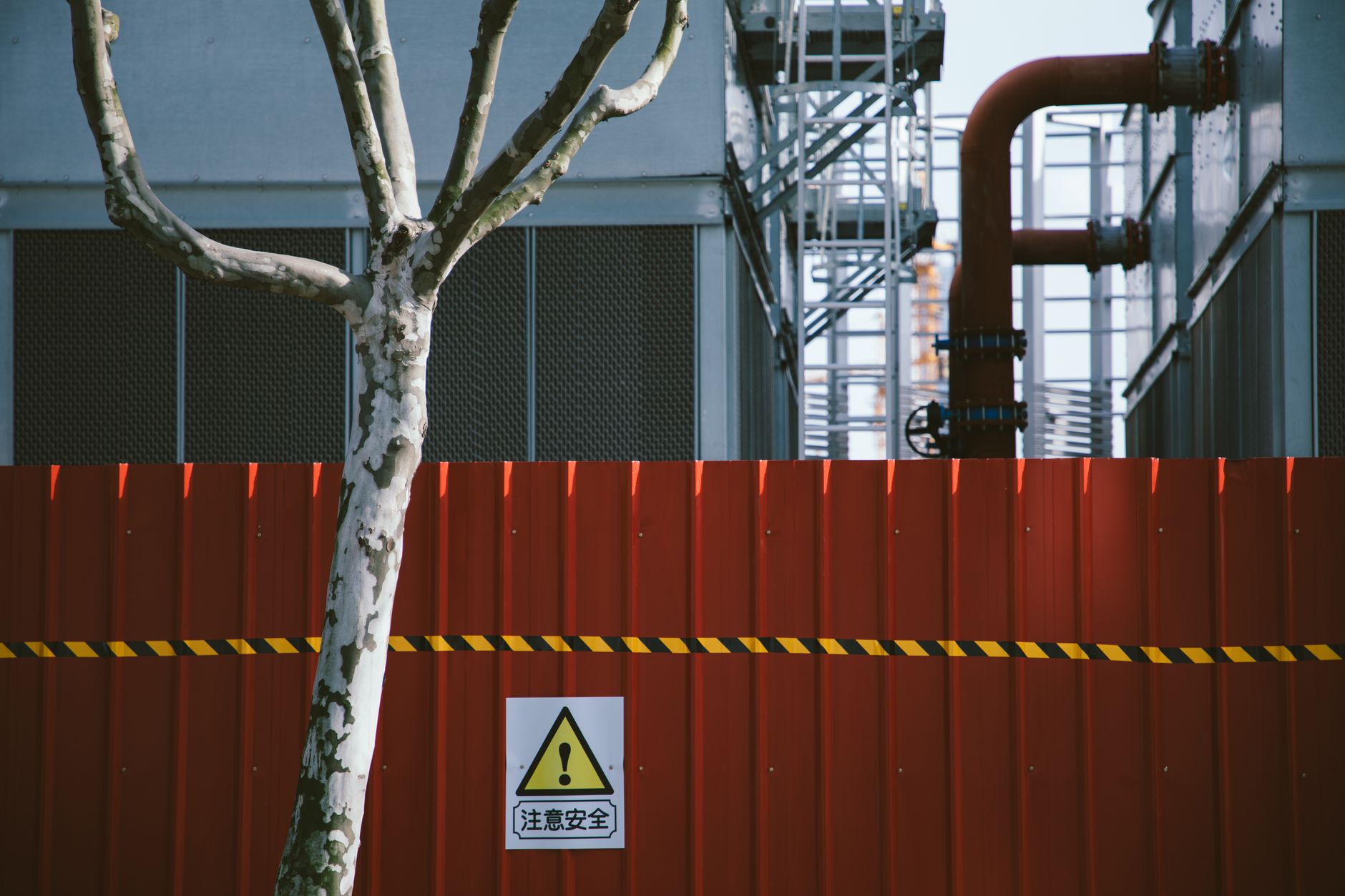 Posted safety fencing and barriers marking an industrial exclusion zone like those around landfill flare pads and blower skids.