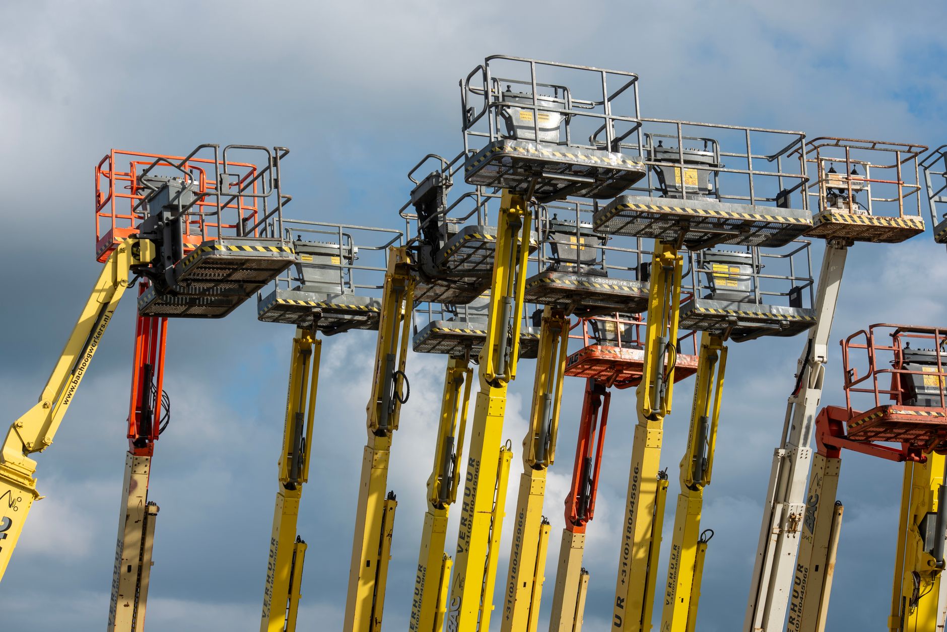Workers using a scissor lift in a long industrial aisle, illustrating the access burden of manual overhead inspections.