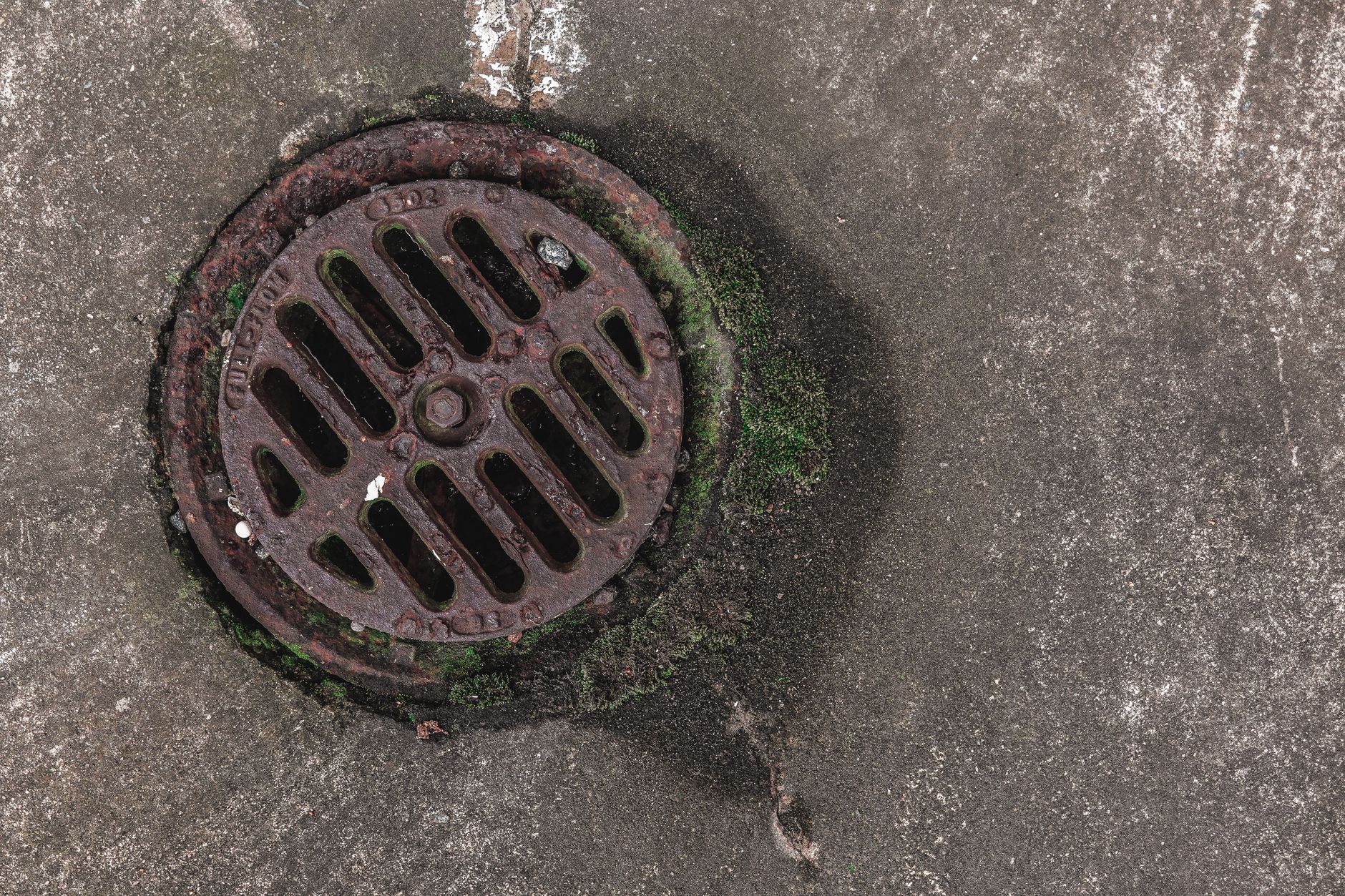 Close view of a roof drain and surrounding membrane where debris, ponding, or overflow marks would show up during a drainage inspection run.