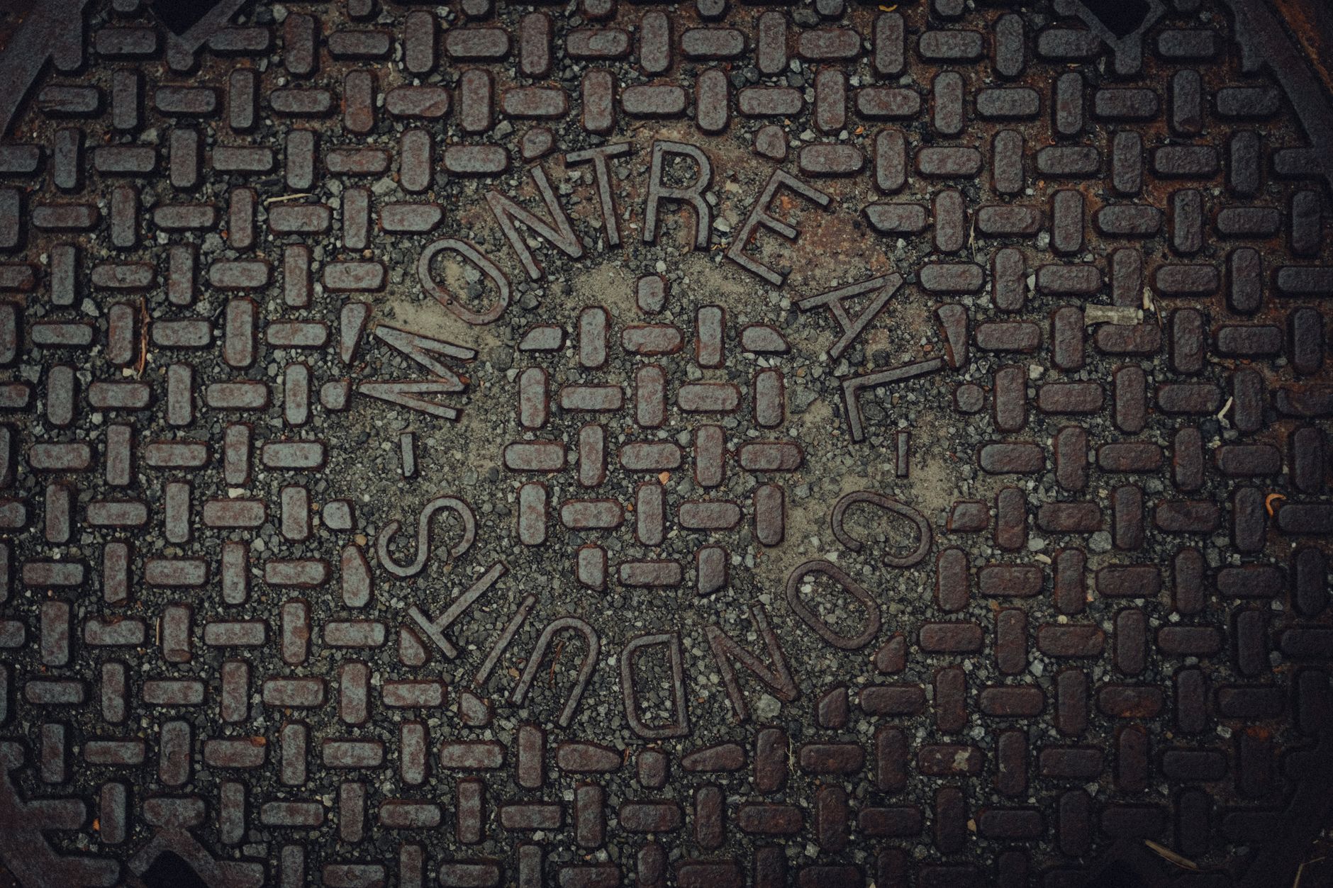 A manhole cover set in pavement, the typical surface access point for launching a tethered tunnel inspection.