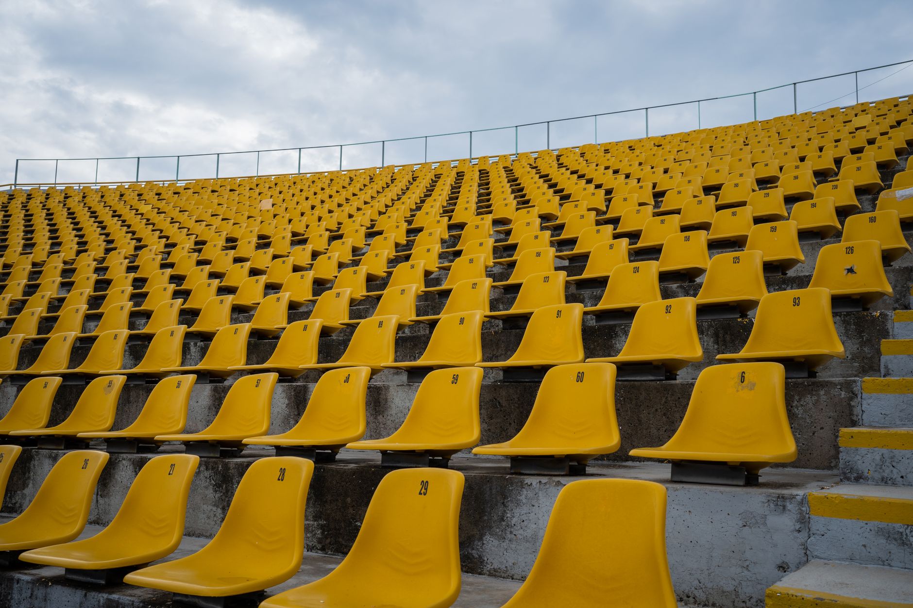 Empty stadium seating bowl viewed from below, where overhead catwalks and rigging require inspection between events.