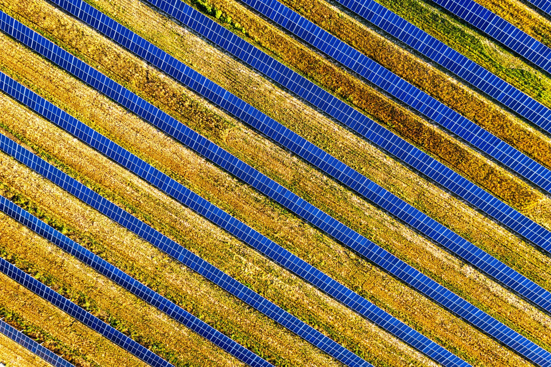 An aerial view shows long repeating rows of solar panels across a sprawling utility-scale site where inspection distance becomes a major operating challenge.