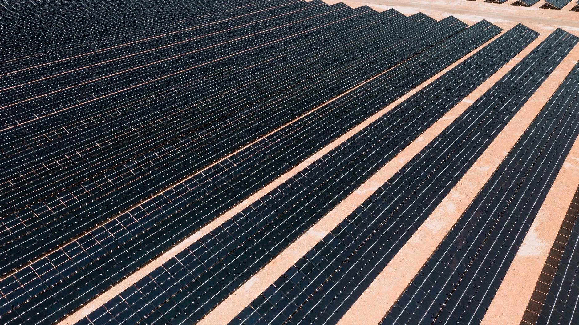 Solar panel rows run across hot, dry ground, illustrating the heat and rough terrain that make long manual inspections harder and riskier.