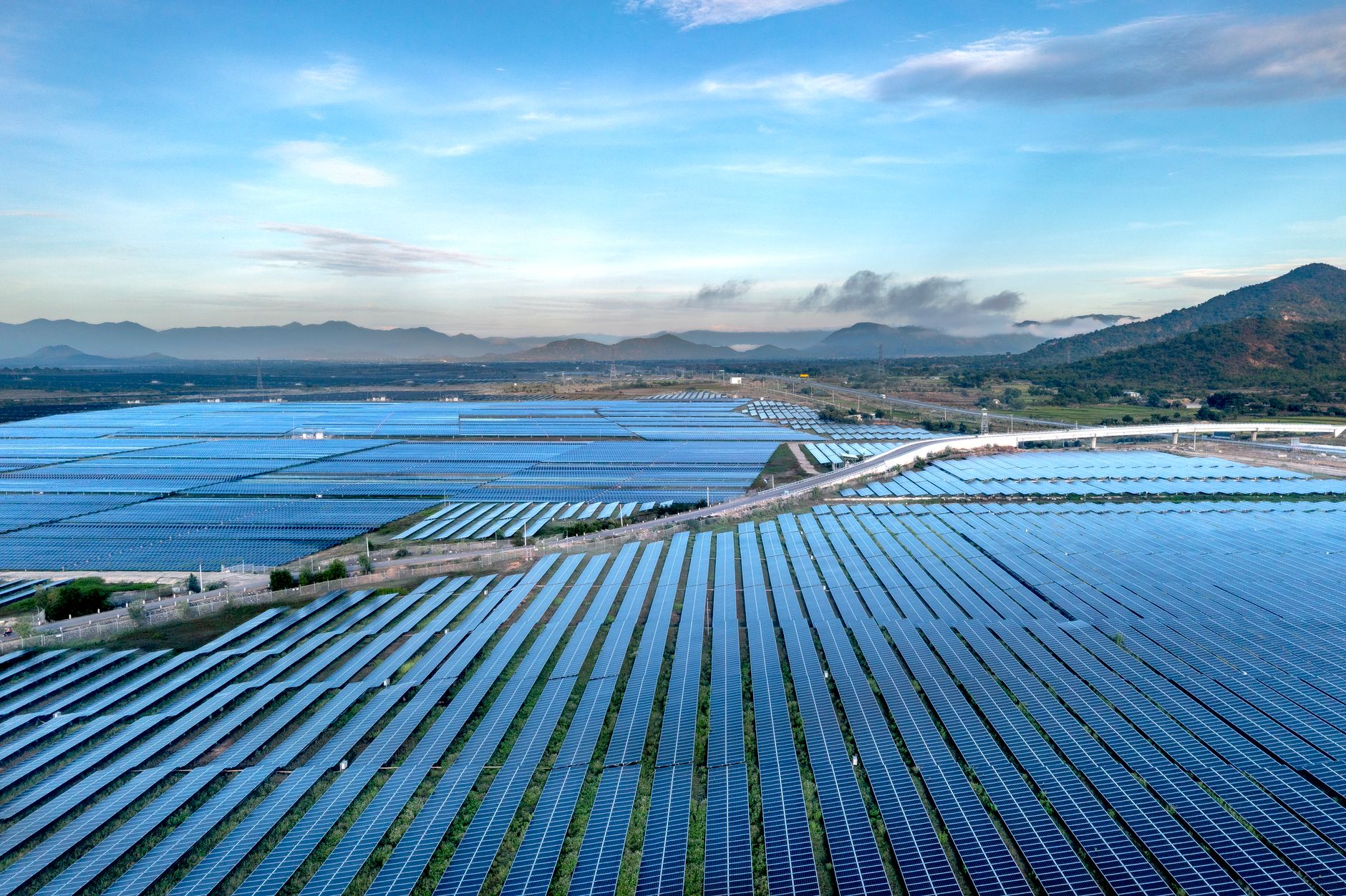 Wide rows of utility-scale solar panels stretch across open land at sunrise, setting the scene for large-site inspection work.