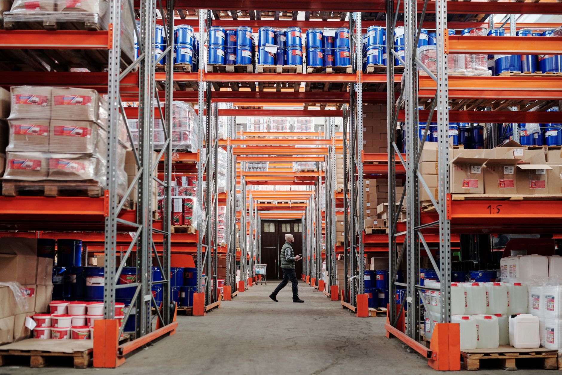 A wide, clean, and well-lit aisle in a modern warehouse, with tall shelving units on either side ready for automated systems.
