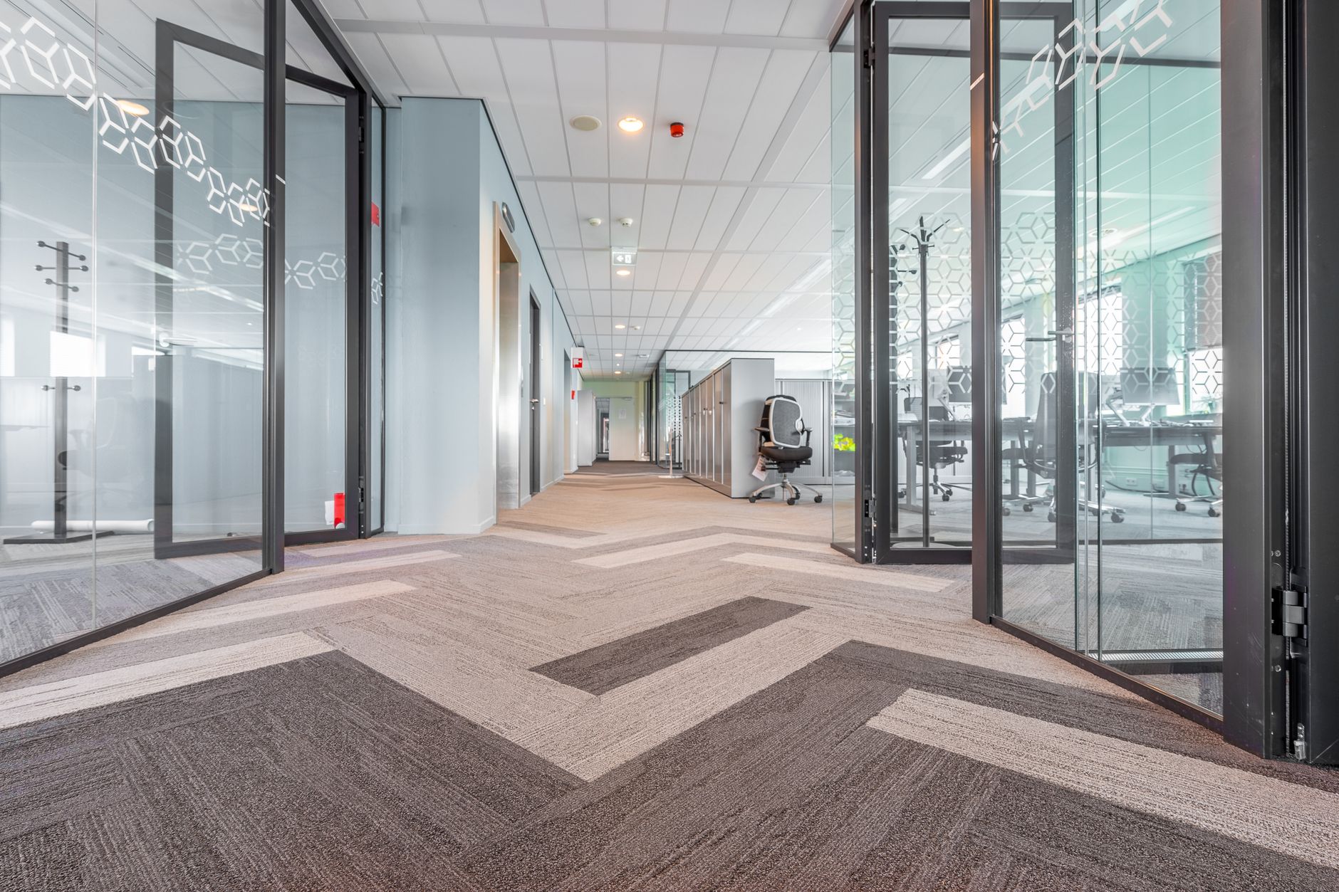 Long office corridor with carpet, doors, and narrow circulation points that can quietly become choke points for delivery routes.