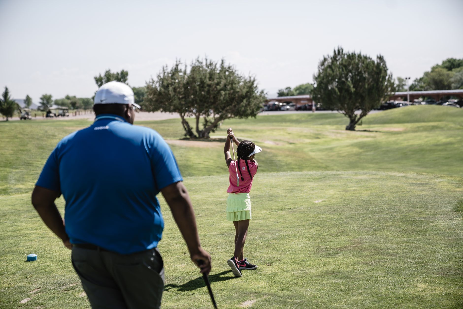 Junior golfers at a Saturday clinic station on a course fairway.